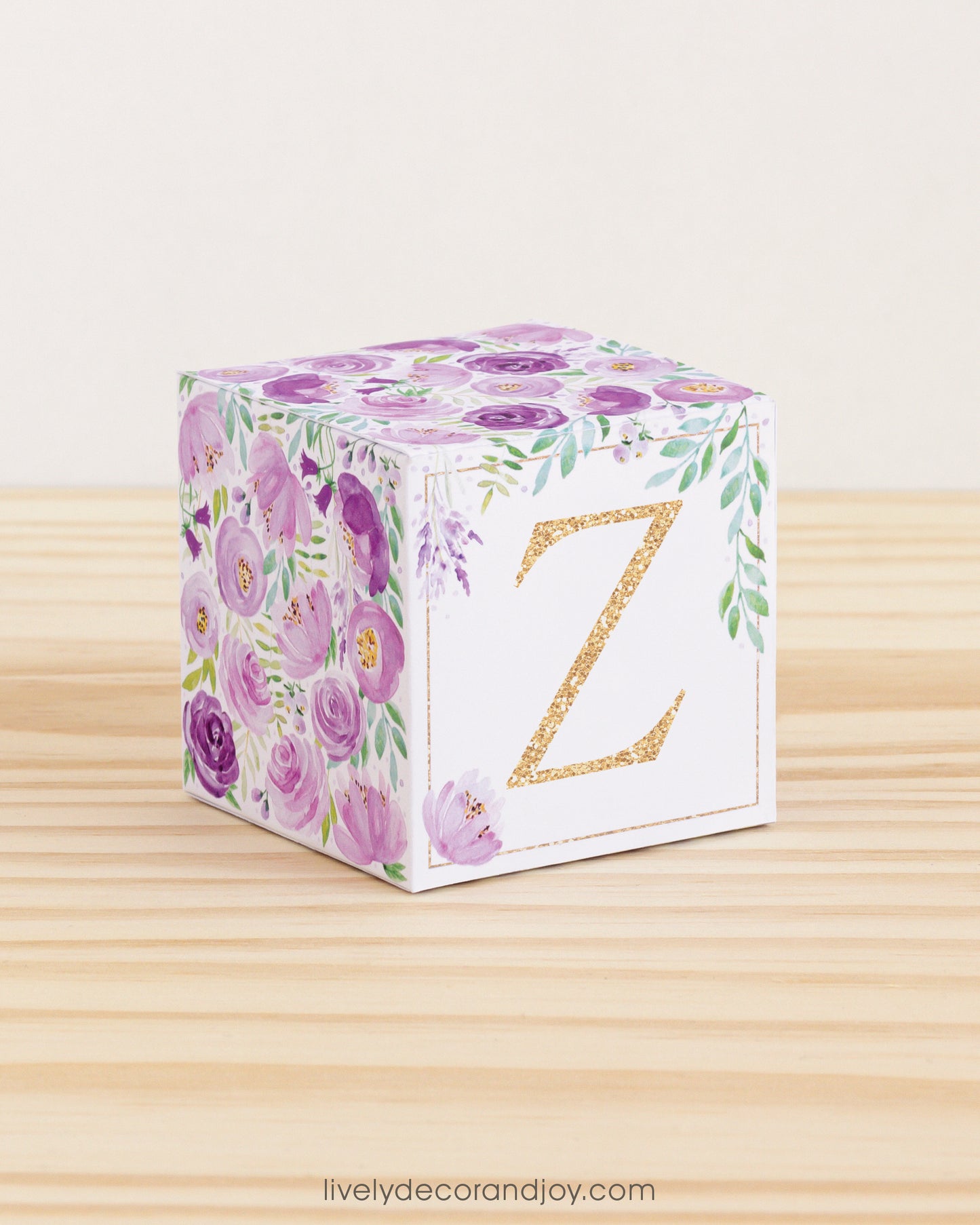 Block made of printed paper with watercolor flowers in purple tones and green leaves. Features a gold letter Z on the front.