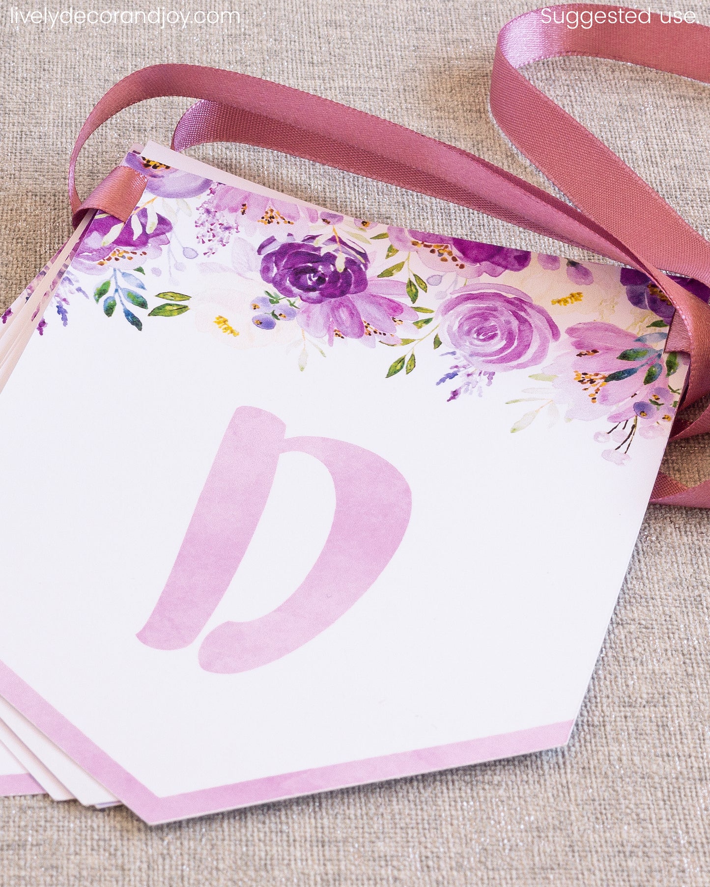 Purple floral flags on a table: a name banner printable set or an anniversary banner. Letters in pink.