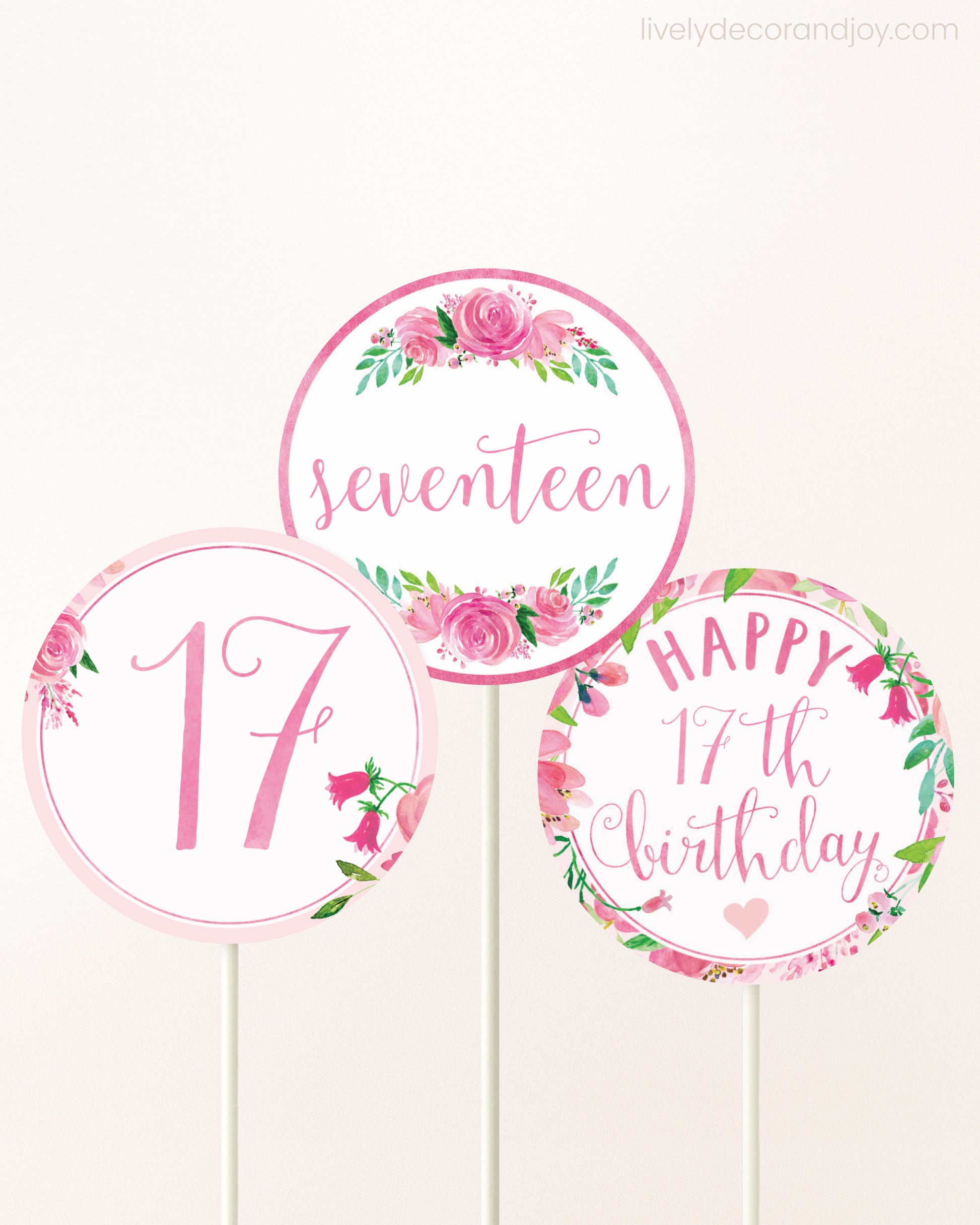 Three cupcakes toppers attached to lollipop sticks. They feature pink watercolor floral designs and pink and gold handwritten text.