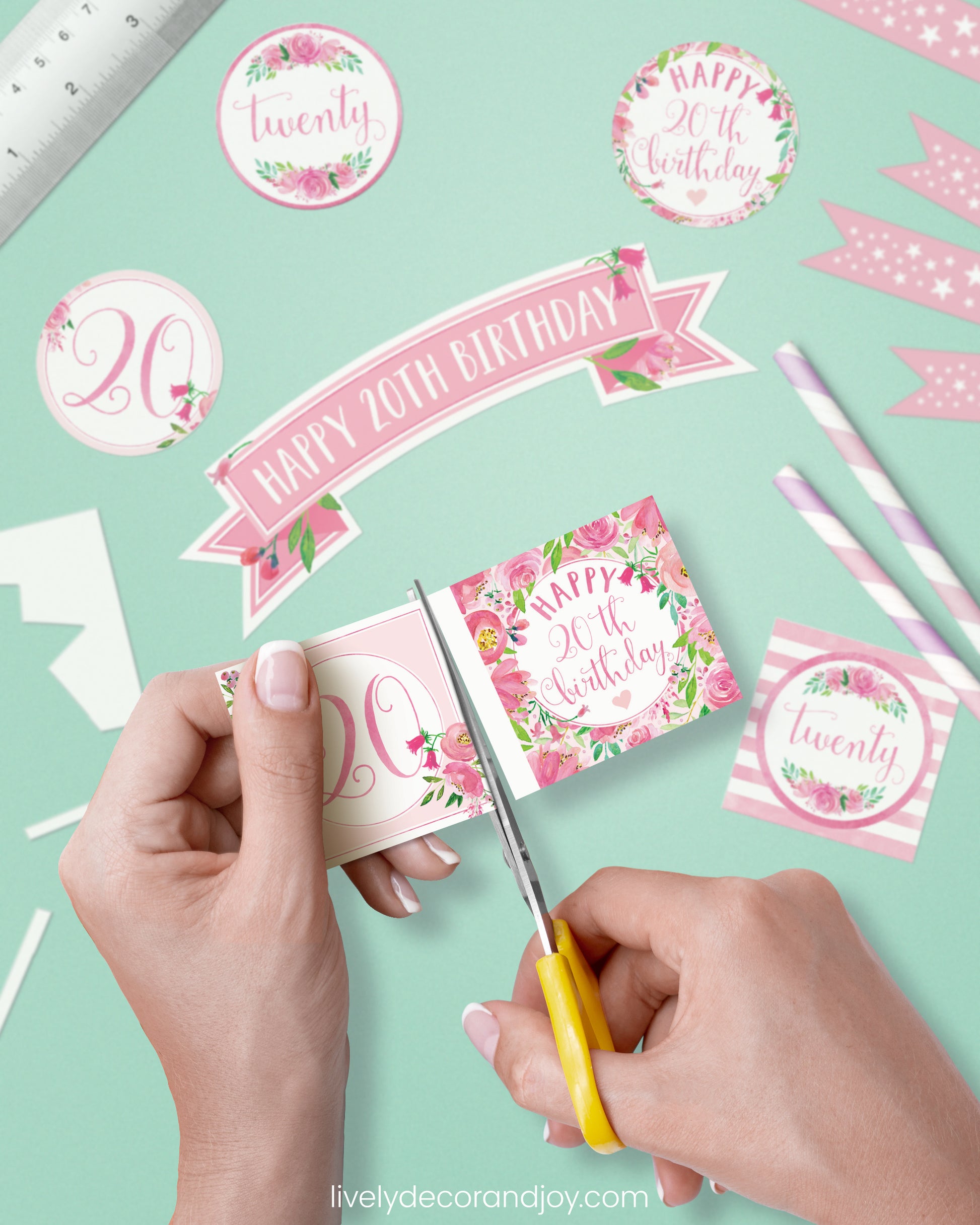 A woman cut a couple of square birthday tags after cutting round party labels, straw flags, and a cake topper.