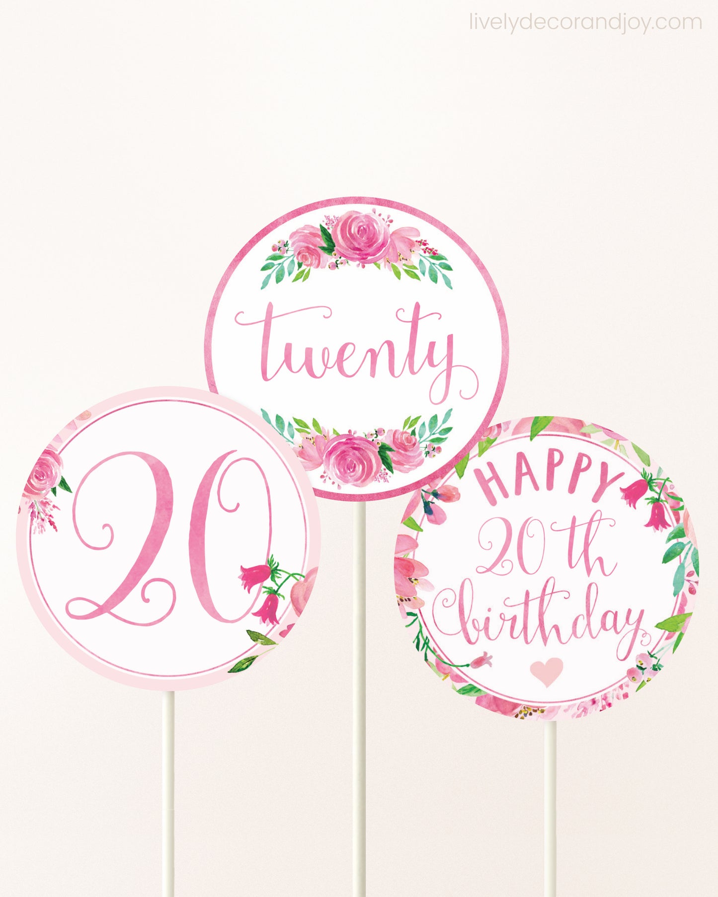 Three cupcakes toppers attached to lollipop sticks. They feature pink watercolor floral designs and pink and gold handwritten text.