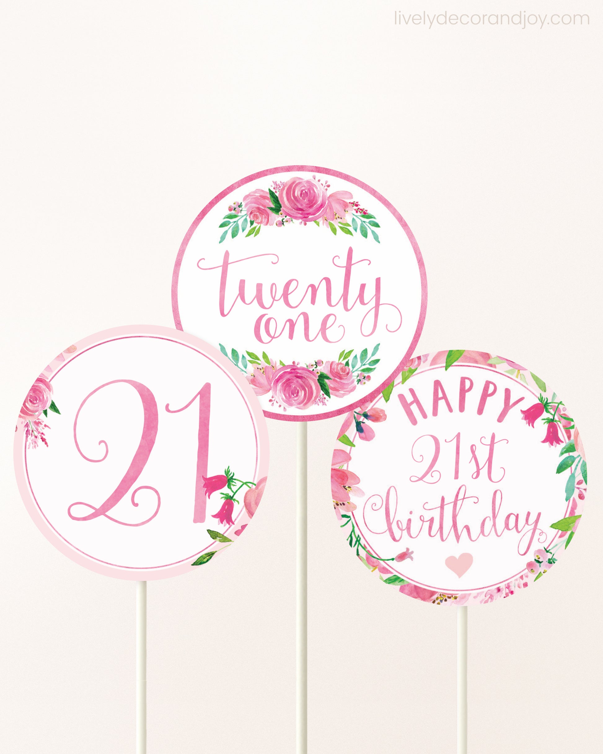Three DIY toppers attached to lollipop sticks. They show printable cupcake topper designs with pink watercolor flowers.