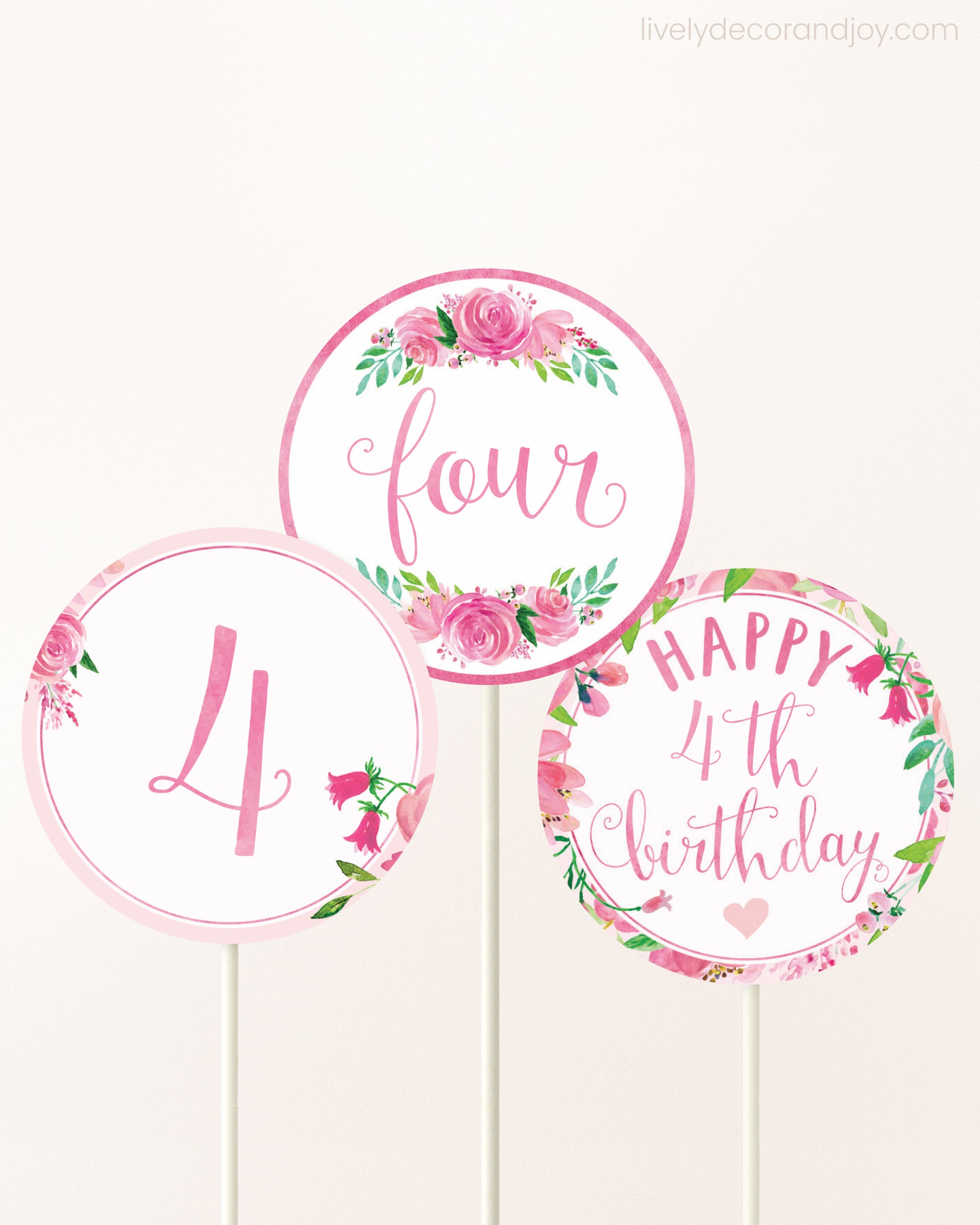 Three cupcakes toppers attached to lollipop sticks. They feature pink watercolor floral designs and pink and gold handwritten text.