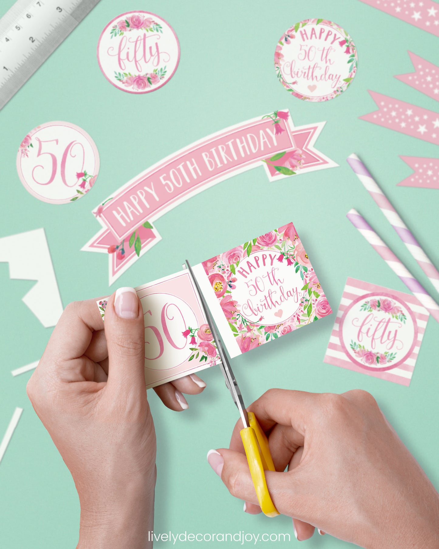 A woman cut a couple of square birthday tags after cutting round party labels, mini flags, and a cake topper.