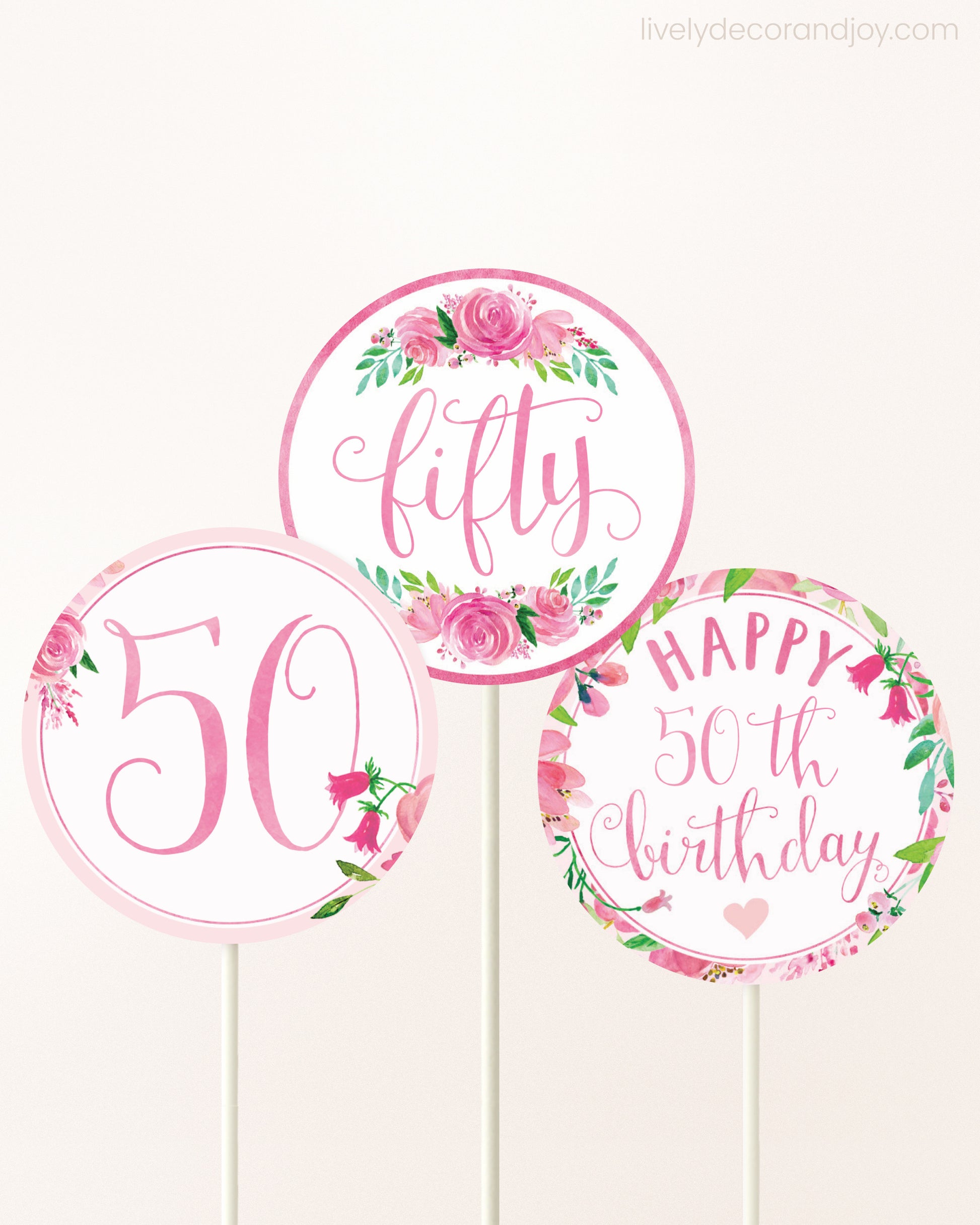 Three DIY toppers attached to lollipop sticks. They show printable cupcake topper designs with pink watercolor flowers.