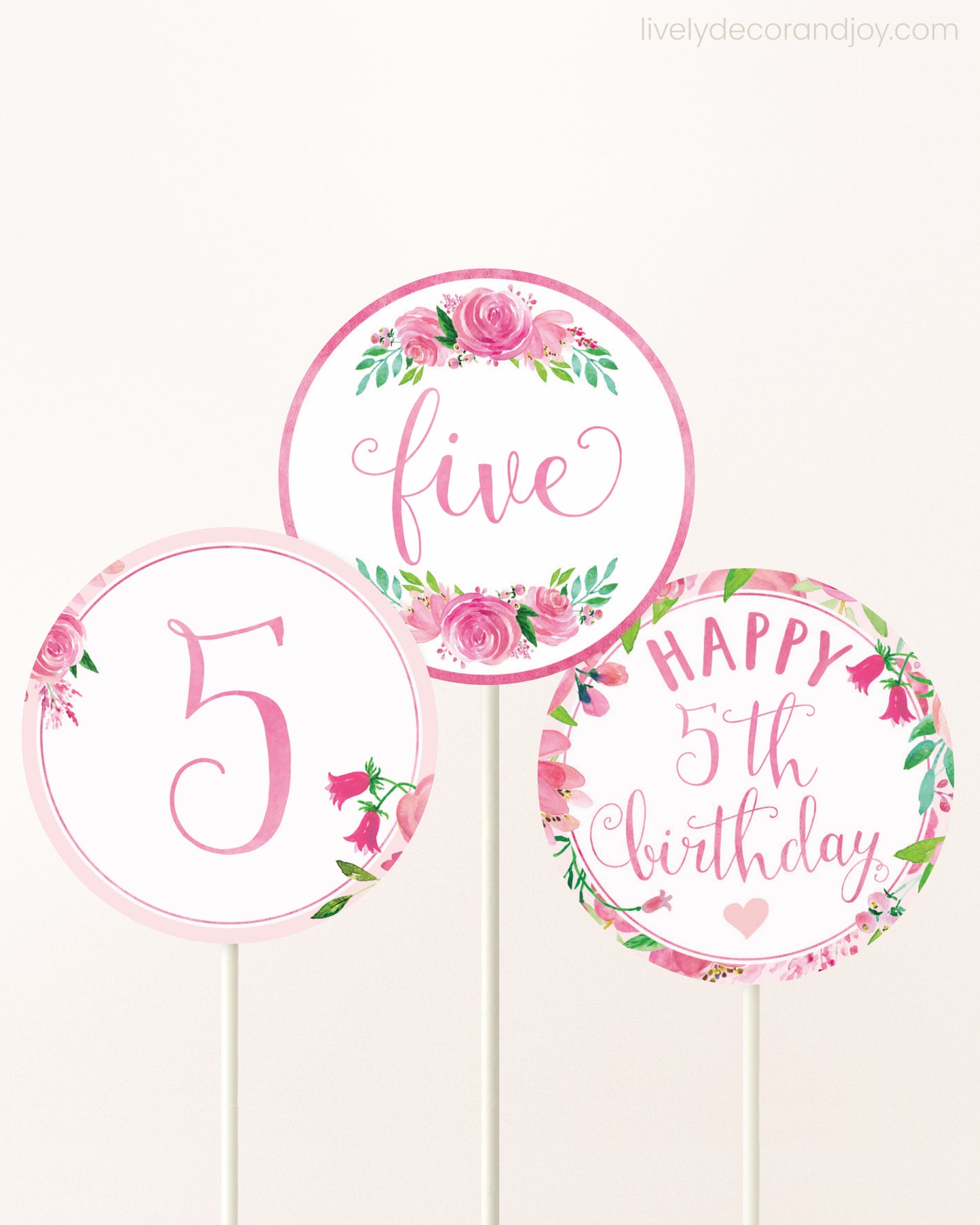 Three DIY toppers attached to lollipop sticks. They show printable cupcake topper designs with pink watercolor flowers.