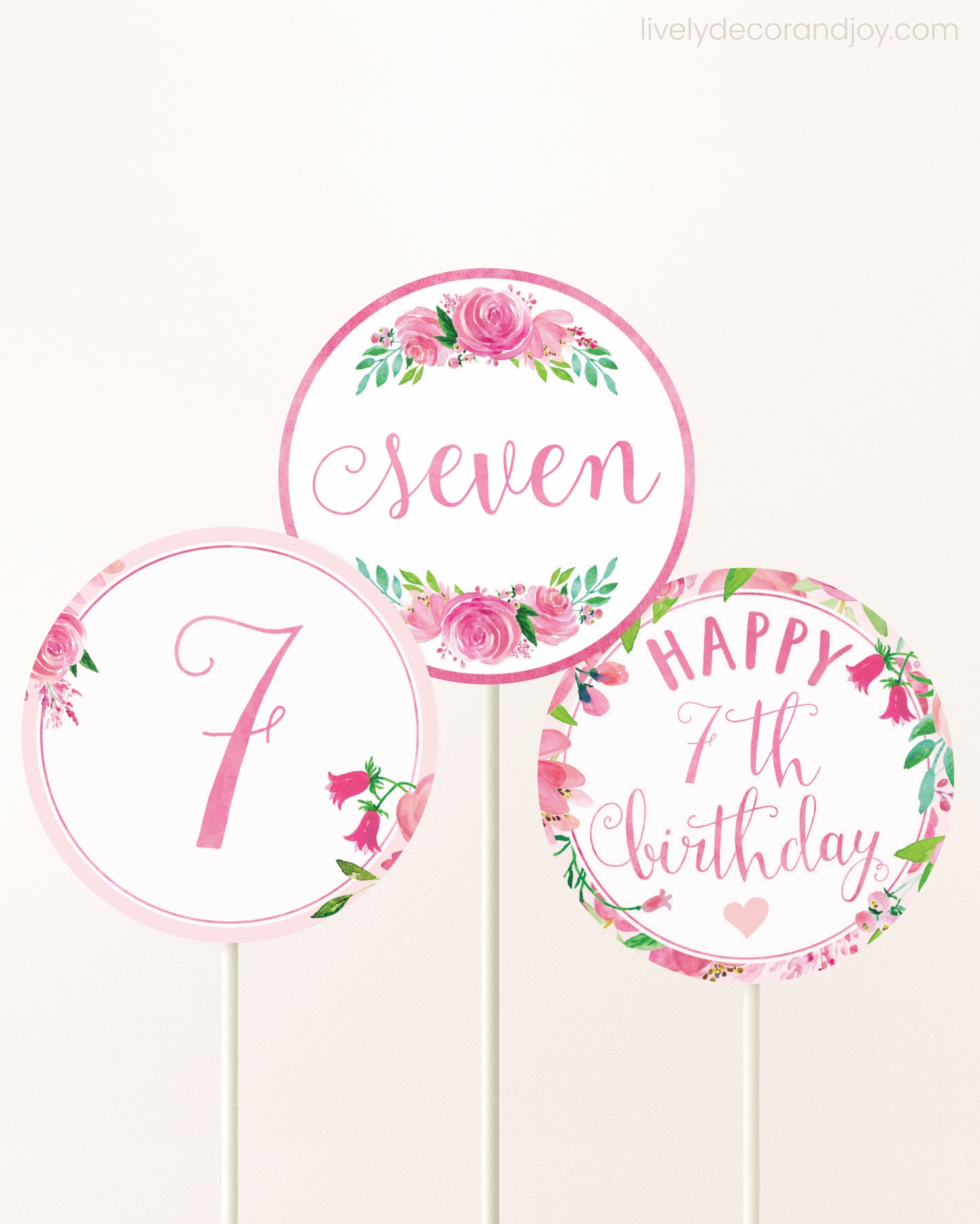 Three DIY toppers attached to lollipop sticks. They show printable cupcake topper designs with pink watercolor flowers.