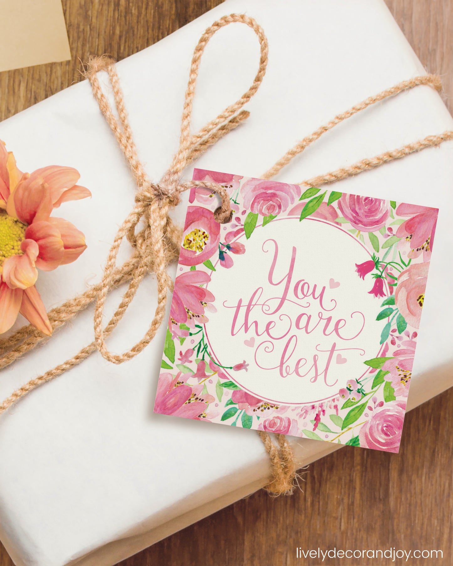 A square gift tag is attached to a congratulations gift on a wooden table.
