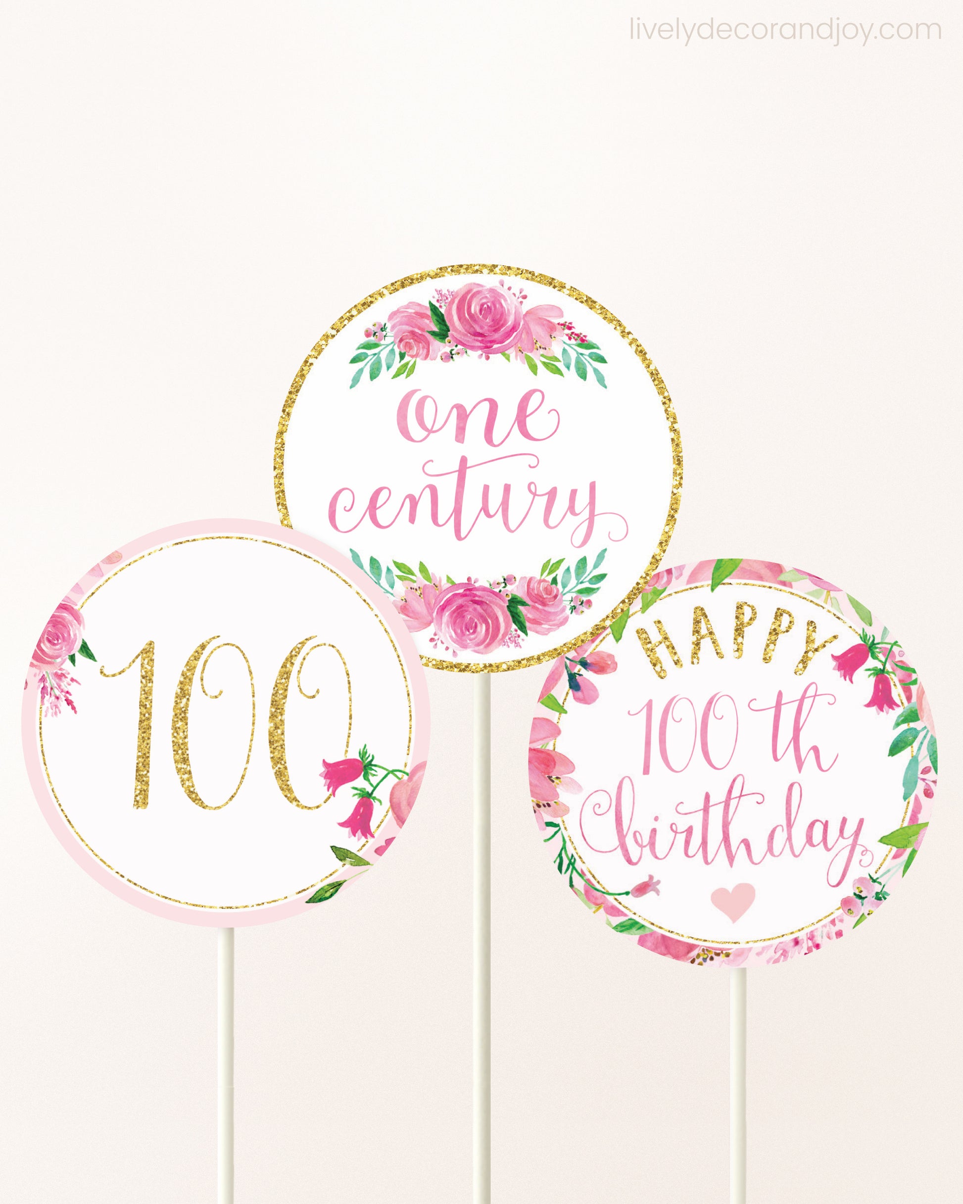 Three cupcakes toppers attached to lollipop sticks. They feature pink watercolor floral designs and pink and gold handwritten text.