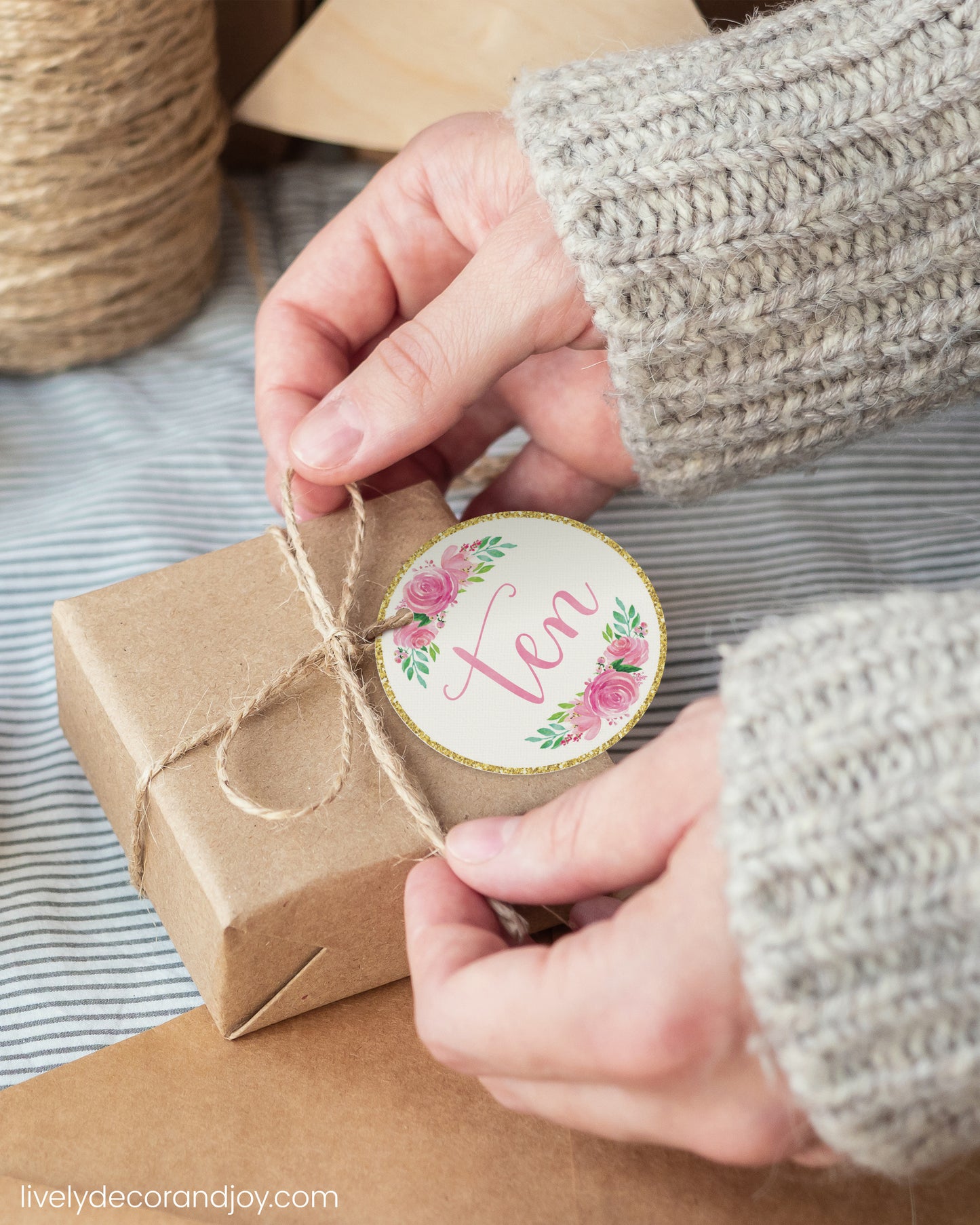 A woman wrap a minimalist gift with a pink watercolor printable gift tag. Hygge or japandi atmosphere.