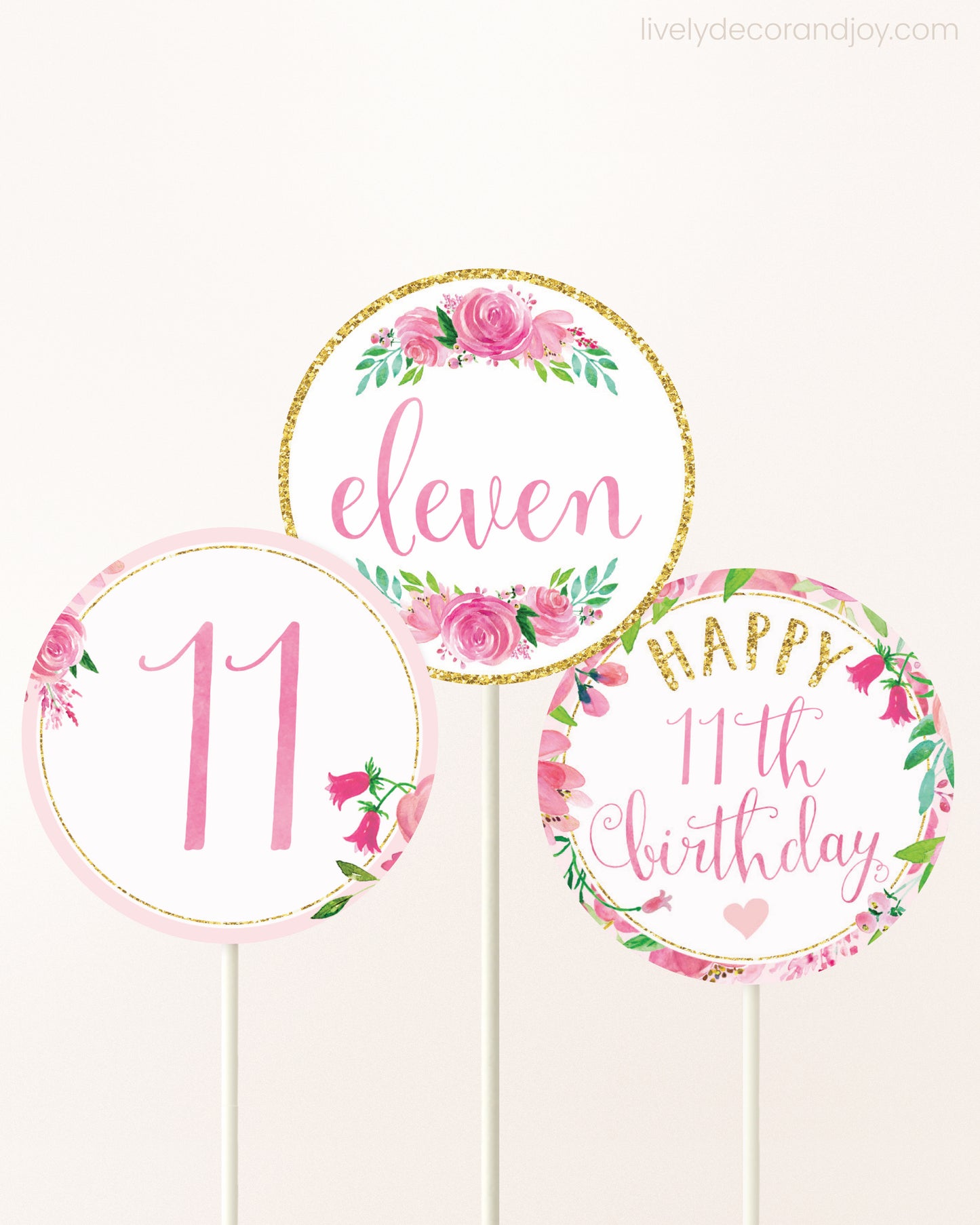Three DIY toppers attached to lollipop sticks. They show printable cupcake topper designs with pink watercolor flowers.