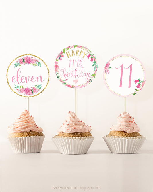 Three cupcakes side by side. Each has a round cupcake topper with pink watercolor flowers and pink and gold letters.