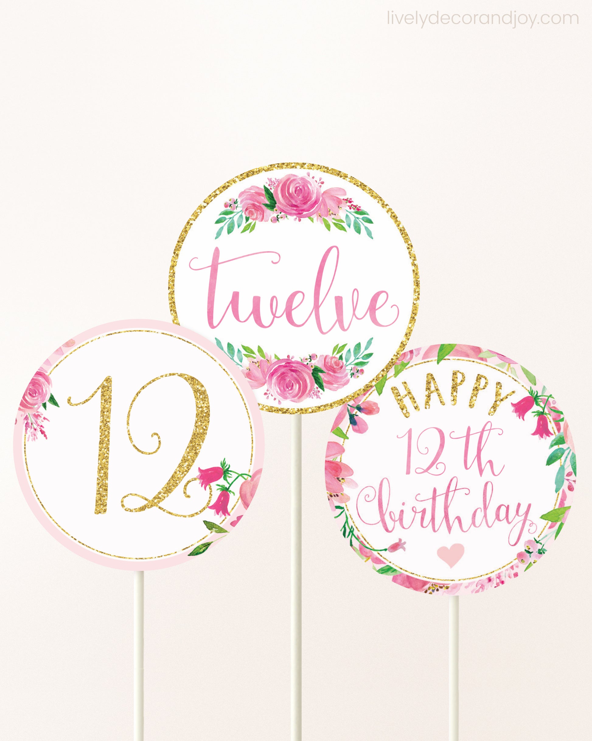 Three cupcakes toppers attached to lollipop sticks. They feature pink watercolor floral designs and pink and gold handwritten text.
