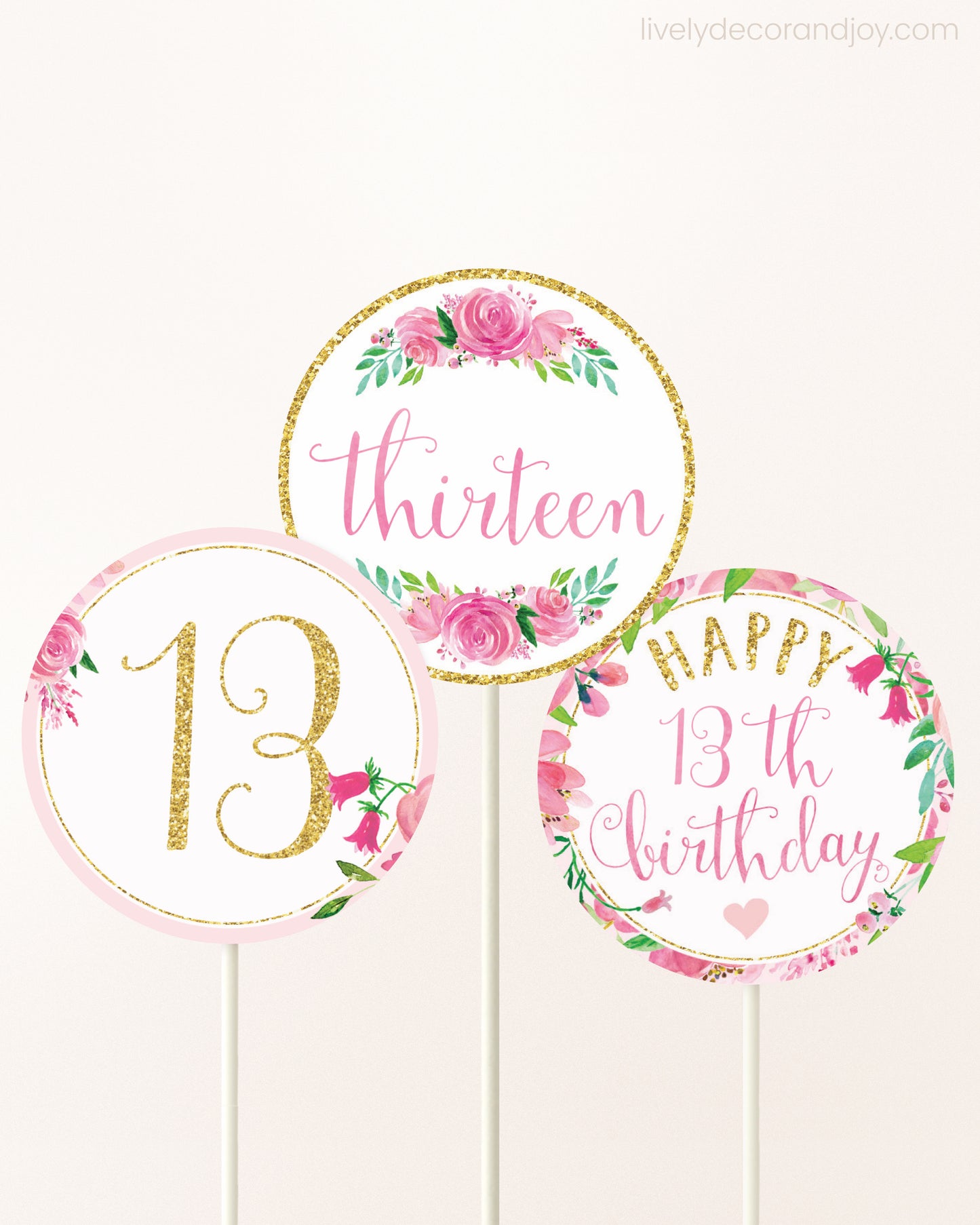 Three DIY toppers attached to lollipop sticks. They show printable cupcake topper designs with pink watercolor flowers.