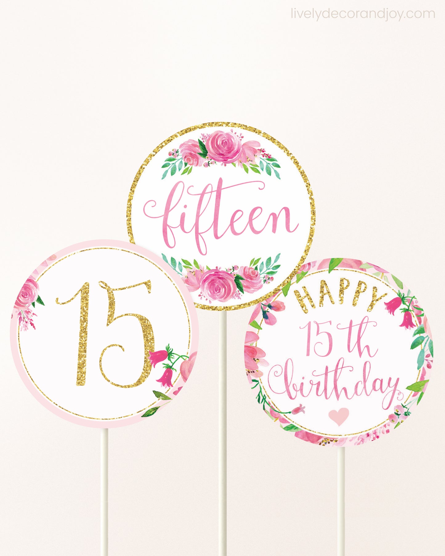 Three cupcakes toppers attached to lollipop sticks. They feature pink watercolor floral designs and pink and gold handwritten text.