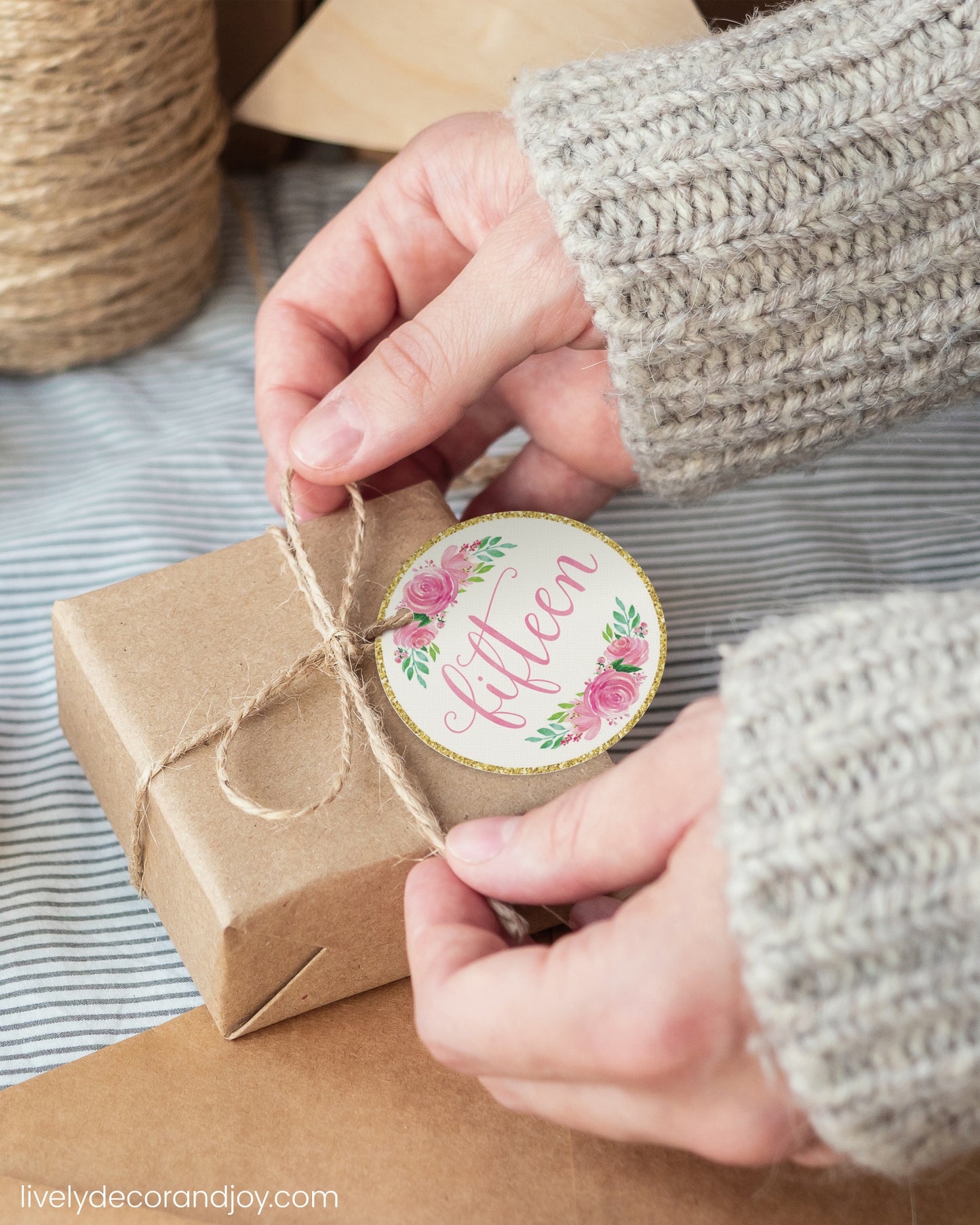 A woman wrap a minimalist gift with a pink watercolor printable gift tag. Hygge or japandi atmosphere.