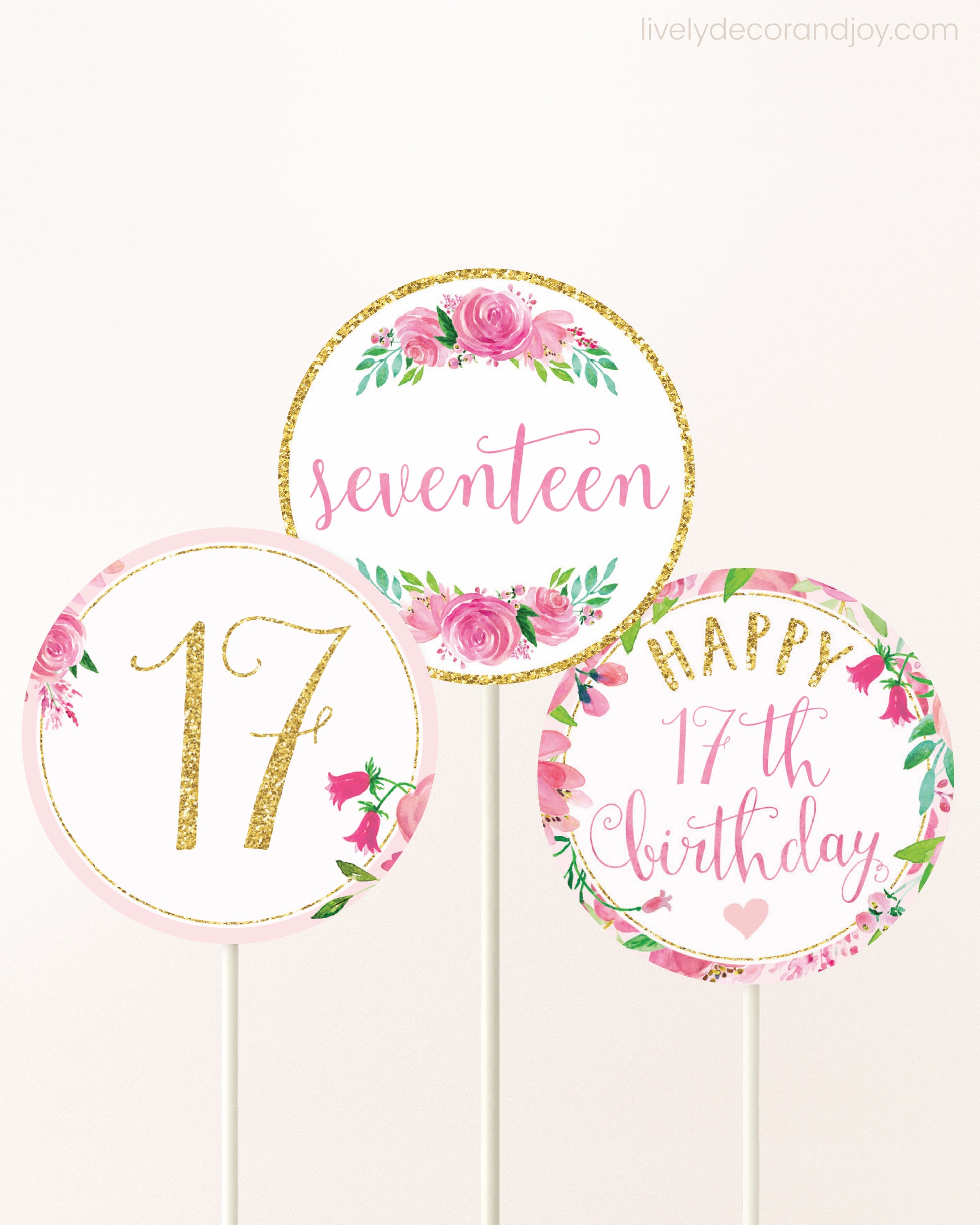Three cupcakes toppers attached to lollipop sticks. They feature pink watercolor floral designs and pink and gold handwritten text.