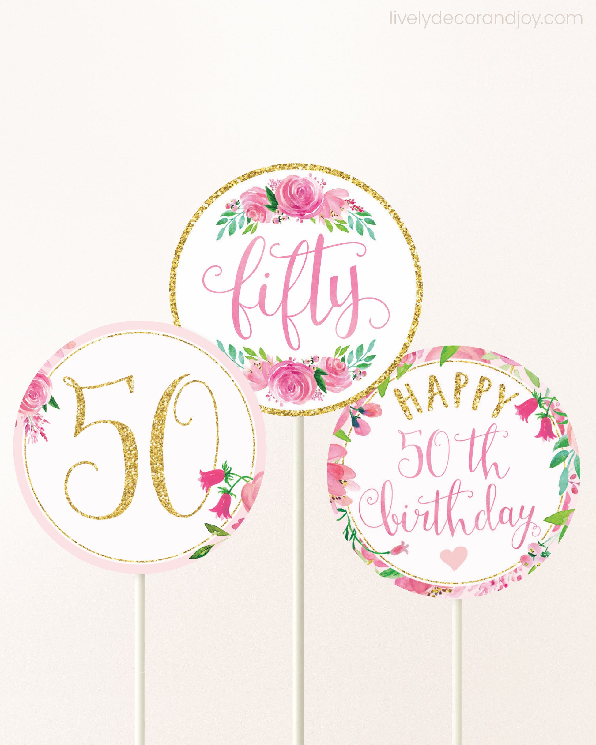 Three DIY toppers attached to lollipop sticks. They show printable cupcake topper designs with pink watercolor flowers.