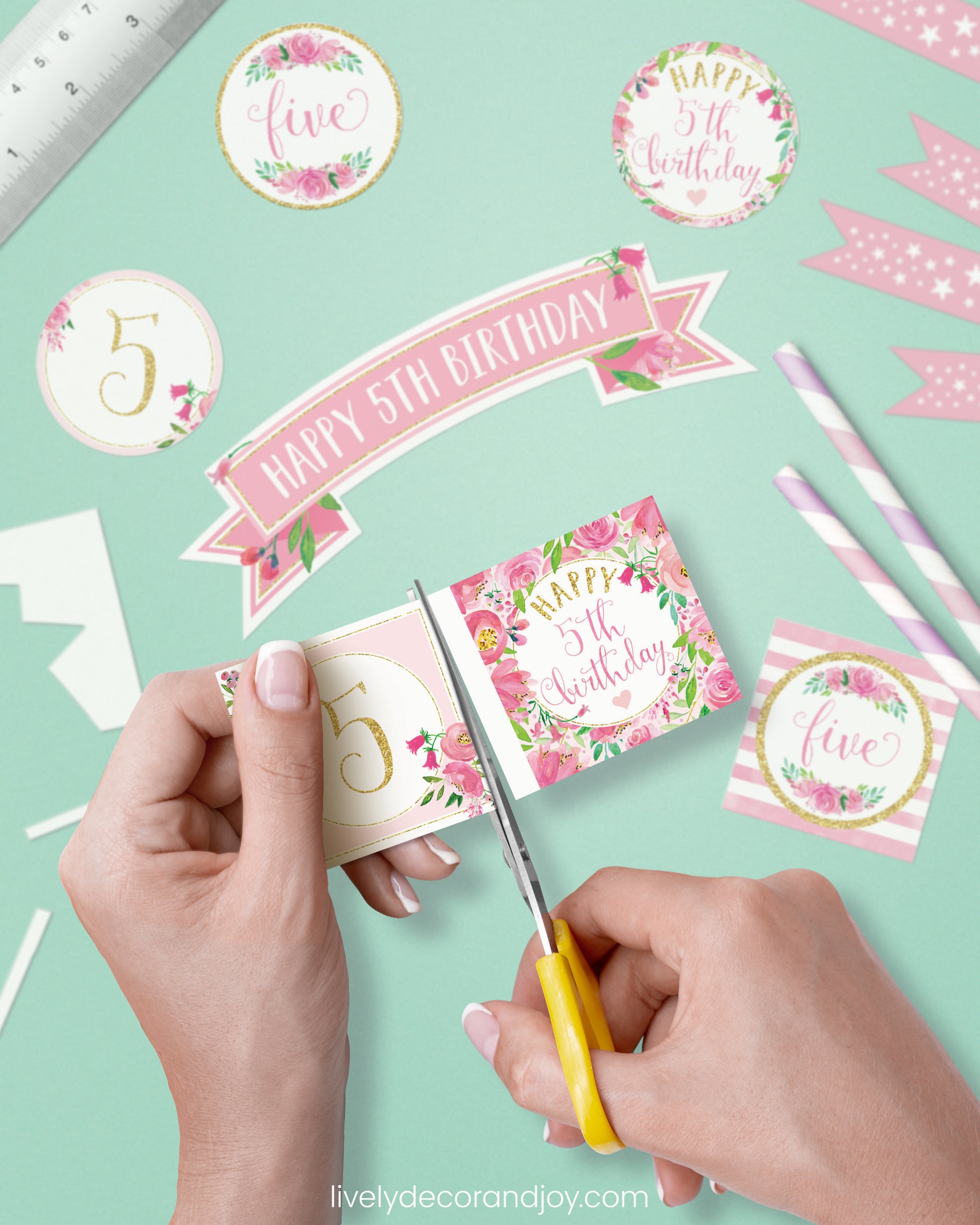A woman cut a couple of square birthday tags after cutting round party labels, mini flags, and a cake topper.