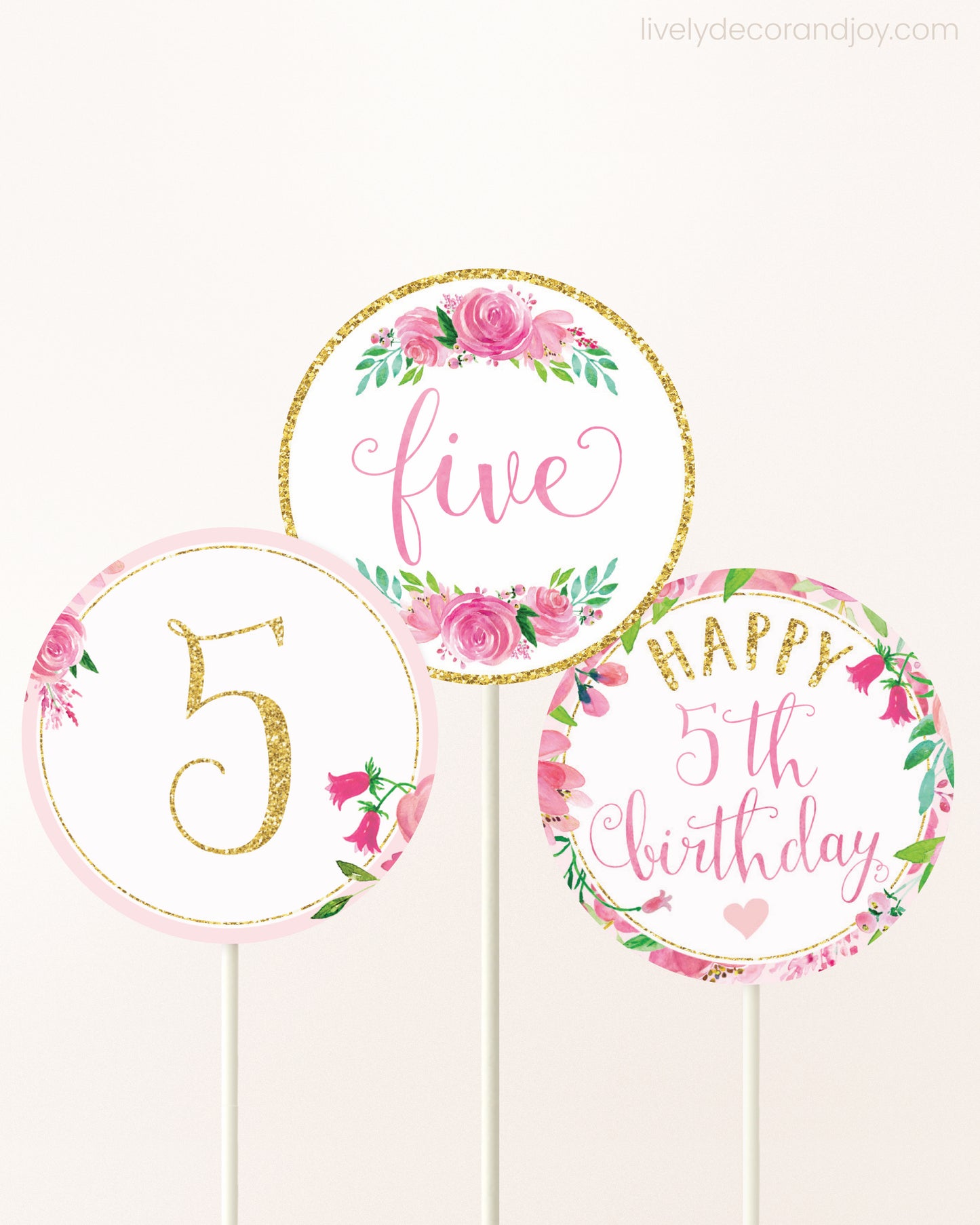 Three DIY toppers attached to lollipop sticks. They show printable cupcake topper designs with pink watercolor flowers.