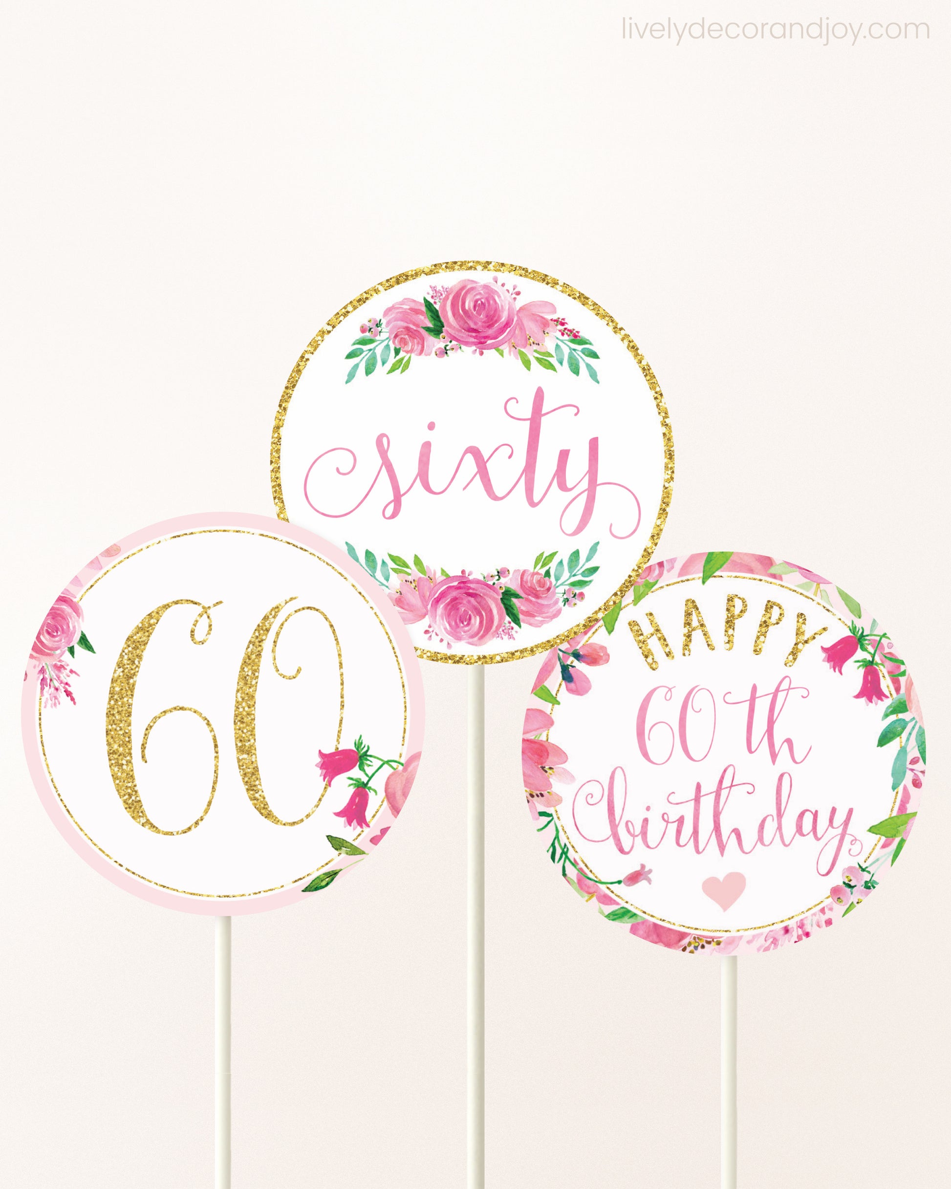 Three DIY toppers attached to lollipop sticks. They show printable cupcake topper designs with pink watercolor flowers.