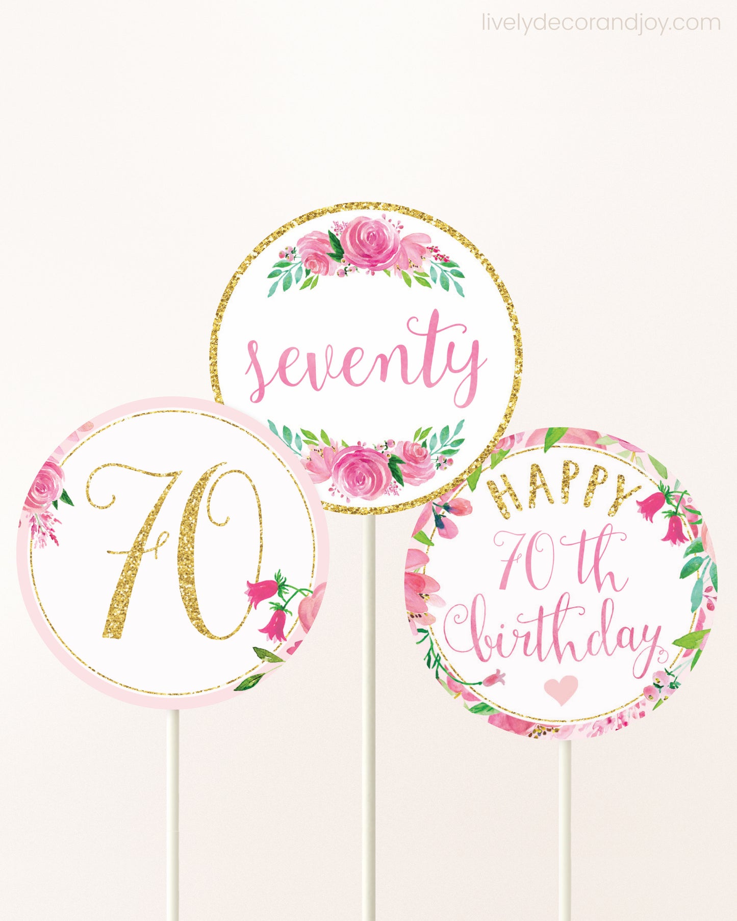 Three cupcakes toppers attached to lollipop sticks. They feature pink watercolor floral designs and pink and gold handwritten text.