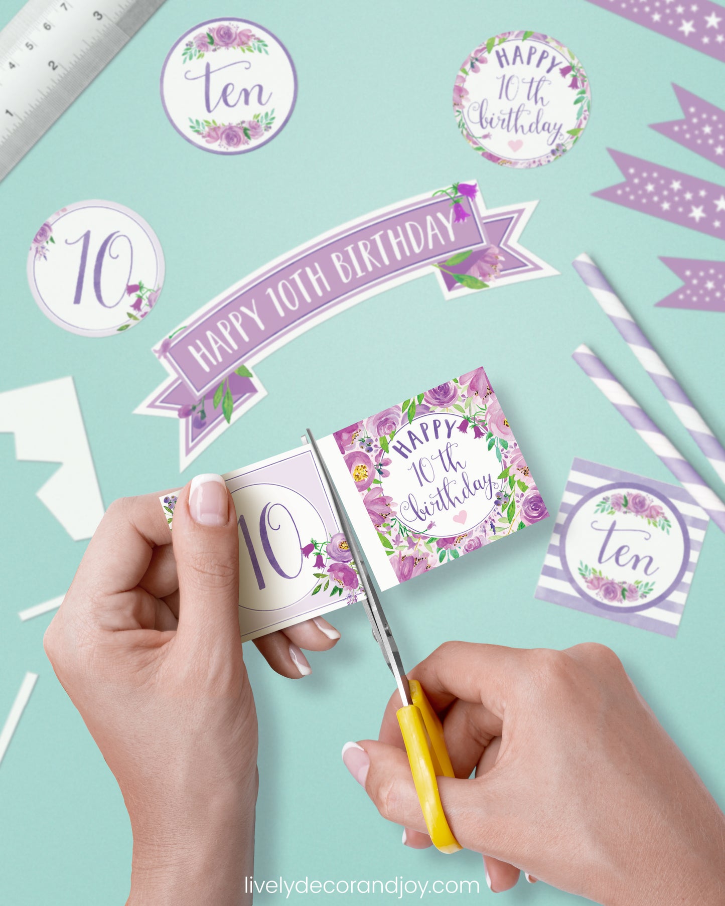 A woman cut a couple of square birthday tags after cutting round party labels, straw flags, and a cake topper.