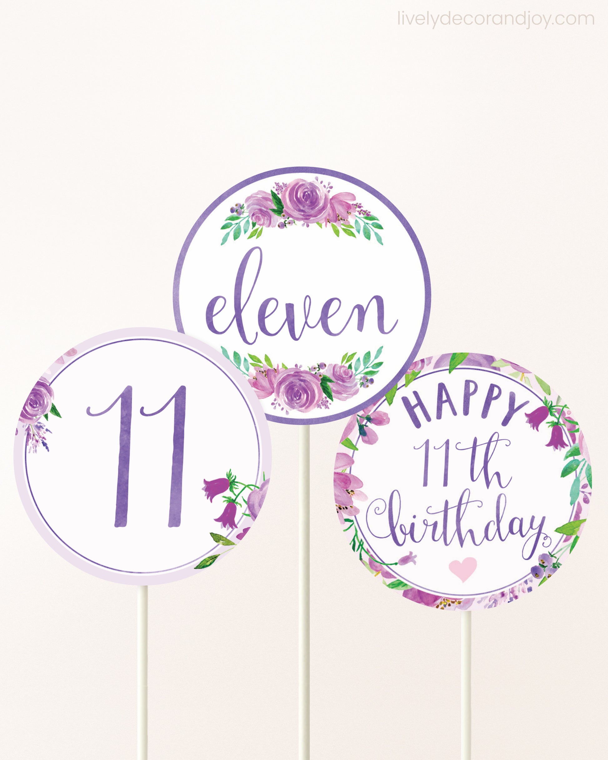 Three DIY toppers attached to lollipop sticks. They show printable cupcake topper designs with purple watercolor flowers.