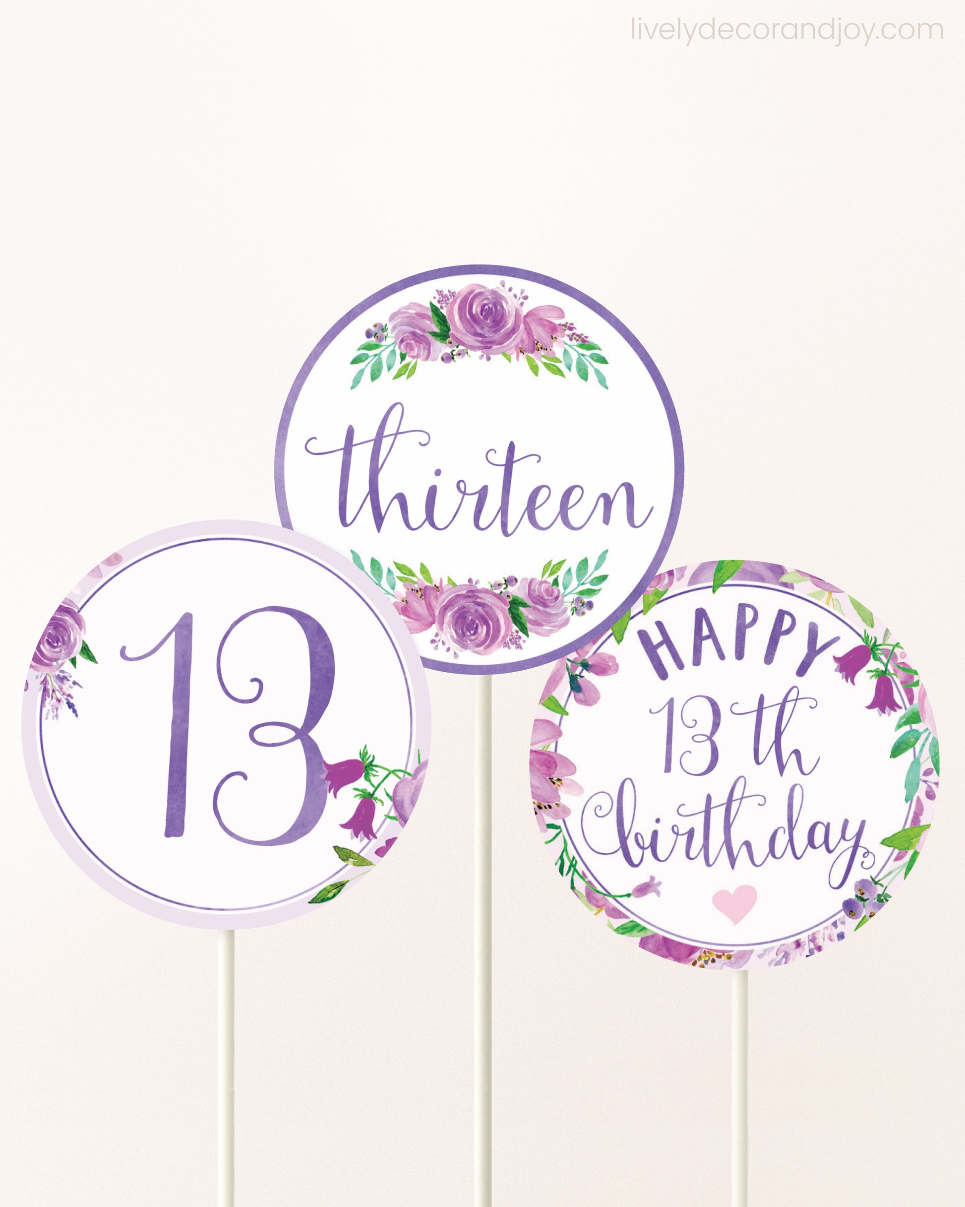 Three DIY toppers attached to lollipop sticks. They show printable cupcake topper designs with purple watercolor flowers.