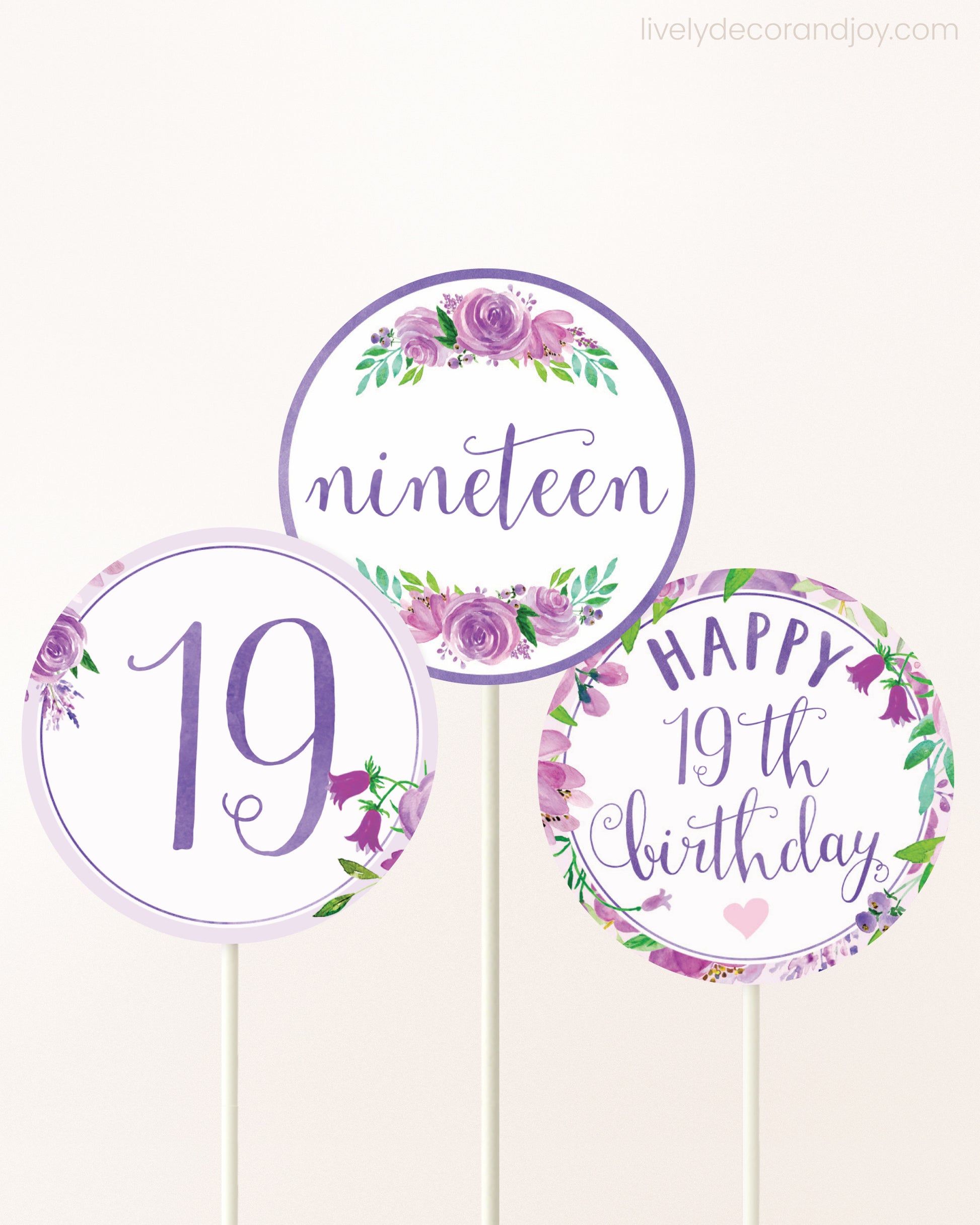 Three DIY toppers attached to lollipop sticks. They show printable cupcake topper designs with purple watercolor flowers.