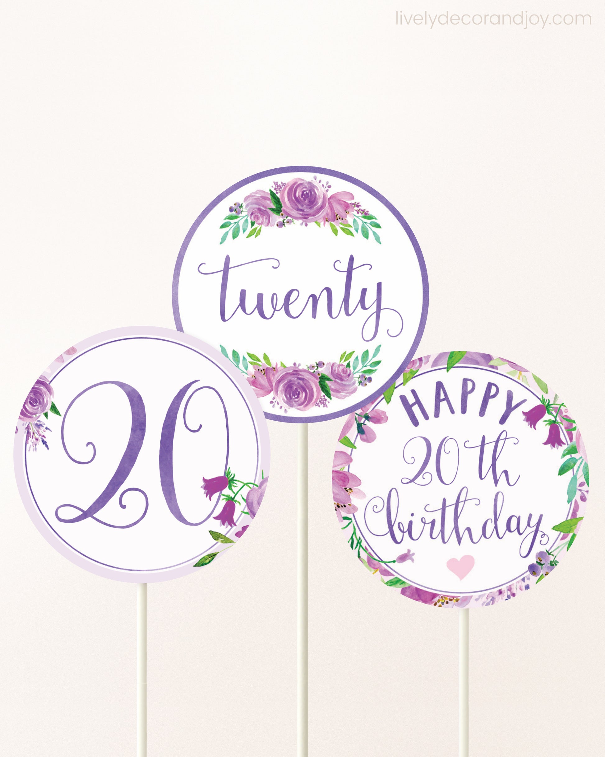 Three cupcakes toppers attached to lollipop sticks. They feature purple watercolor floral designs and purple and gold handwritten text.