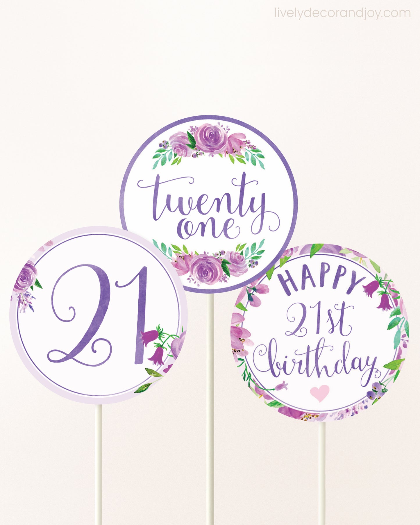 Three DIY toppers attached to lollipop sticks. They show printable cupcake topper designs with purple watercolor flowers.