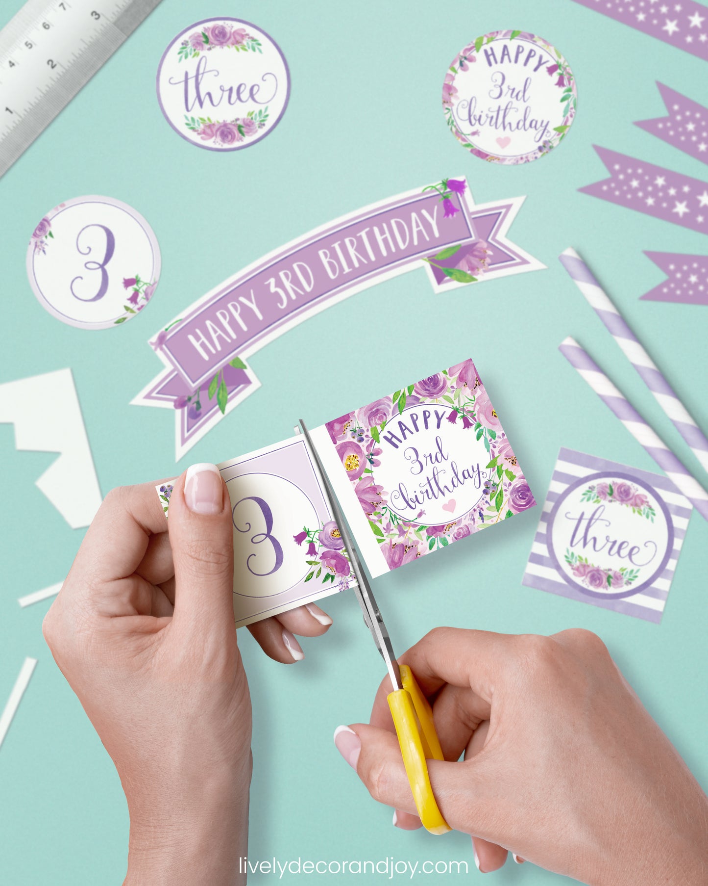 A woman cut a couple of square birthday tags after cutting round party labels, mini flags, and a cake topper.