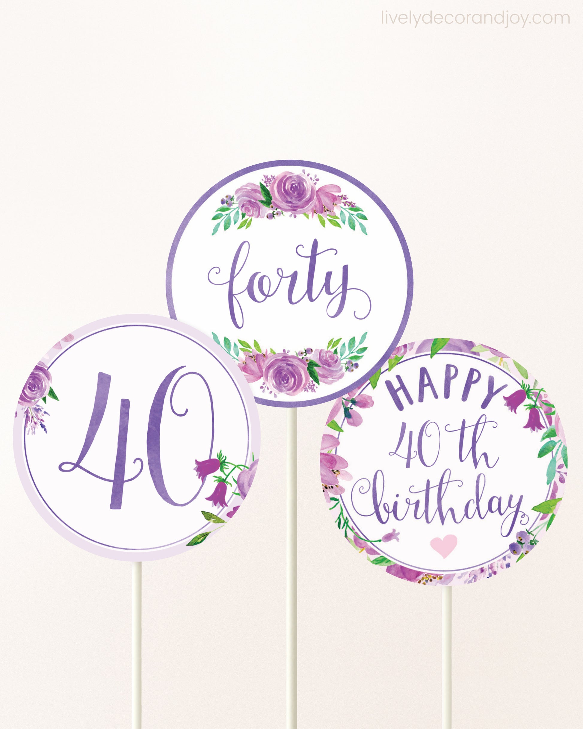 Three DIY toppers attached to lollipop sticks. They show printable cupcake topper designs with purple watercolor flowers.