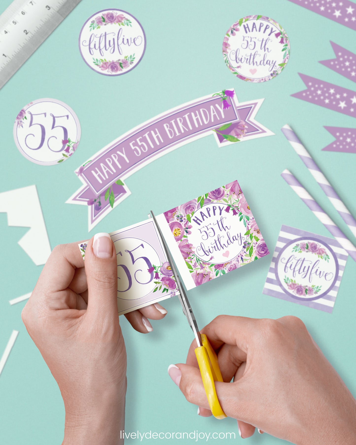 A woman cut a couple of square birthday tags after cutting round party labels, straw flags, and a cake topper.