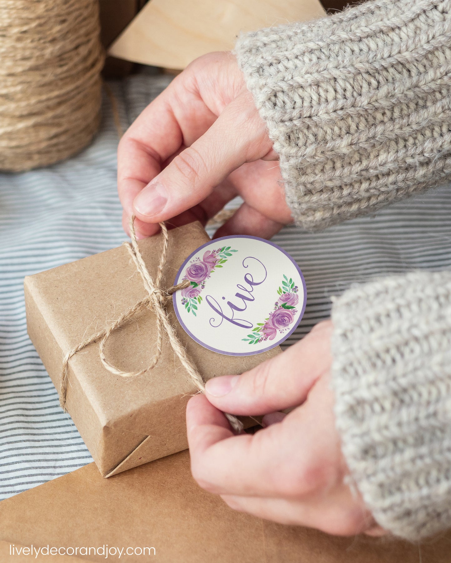 A woman wrap a simple gift with a purple watercolor printable gift tag.