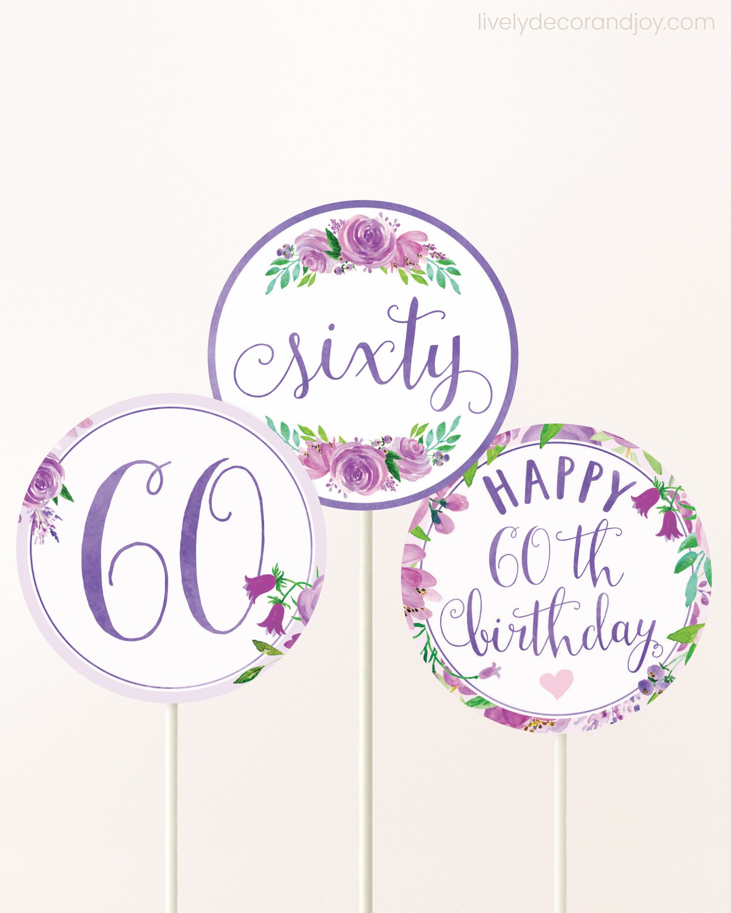 Three DIY toppers attached to lollipop sticks. They show printable cupcake topper designs with purple watercolor flowers.