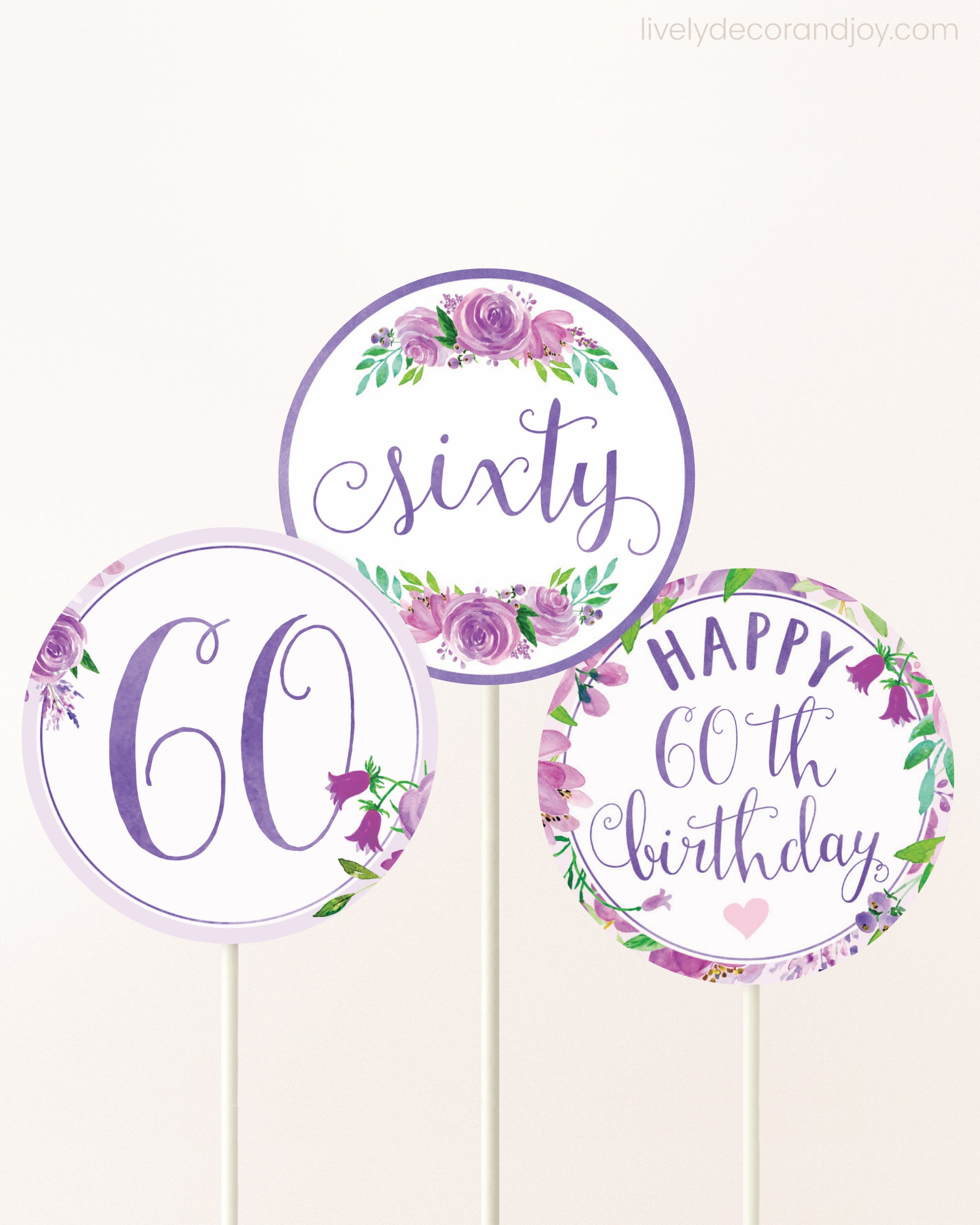 Three DIY toppers attached to lollipop sticks. They show printable cupcake topper designs with purple watercolor flowers.