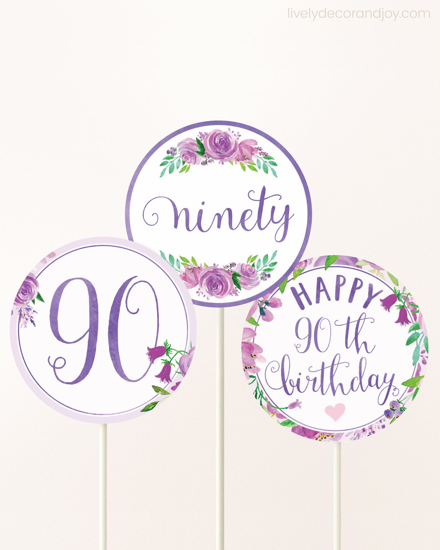 Three DIY toppers attached to lollipop sticks. They show printable cupcake topper designs with purple watercolor flowers.