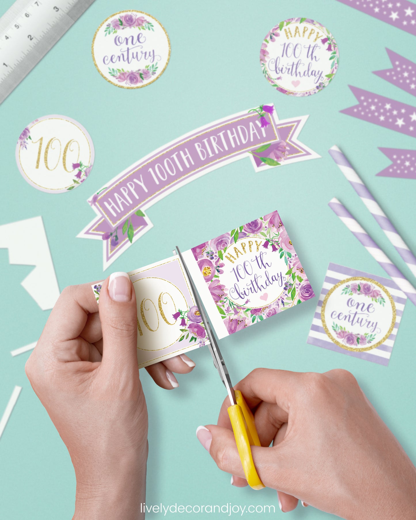 A woman cut a couple of square birthday tags after cutting round party labels, straw flags, and a cake topper.
