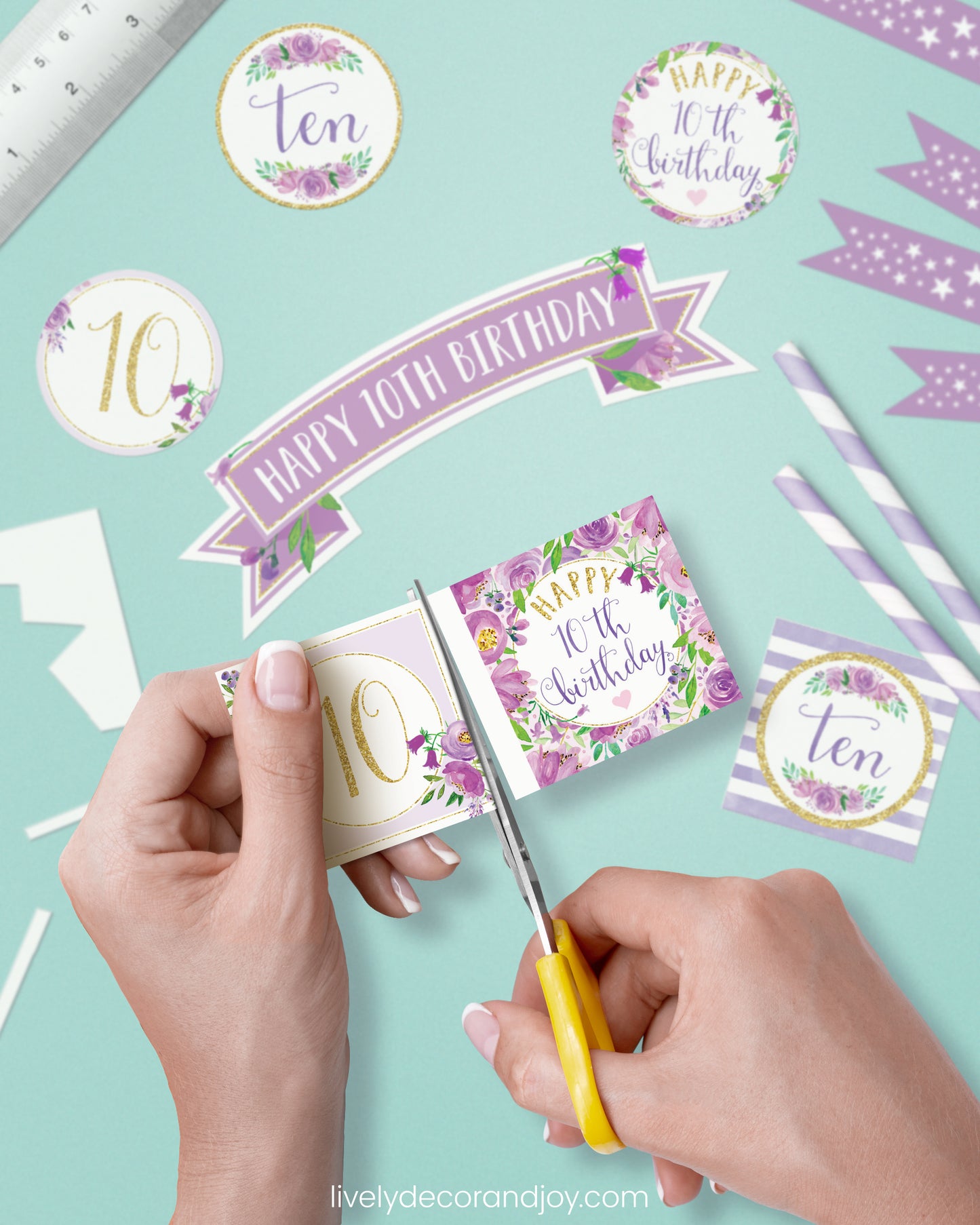 A woman cut a couple of square birthday tags after cutting round party labels, straw flags, and a cake topper.