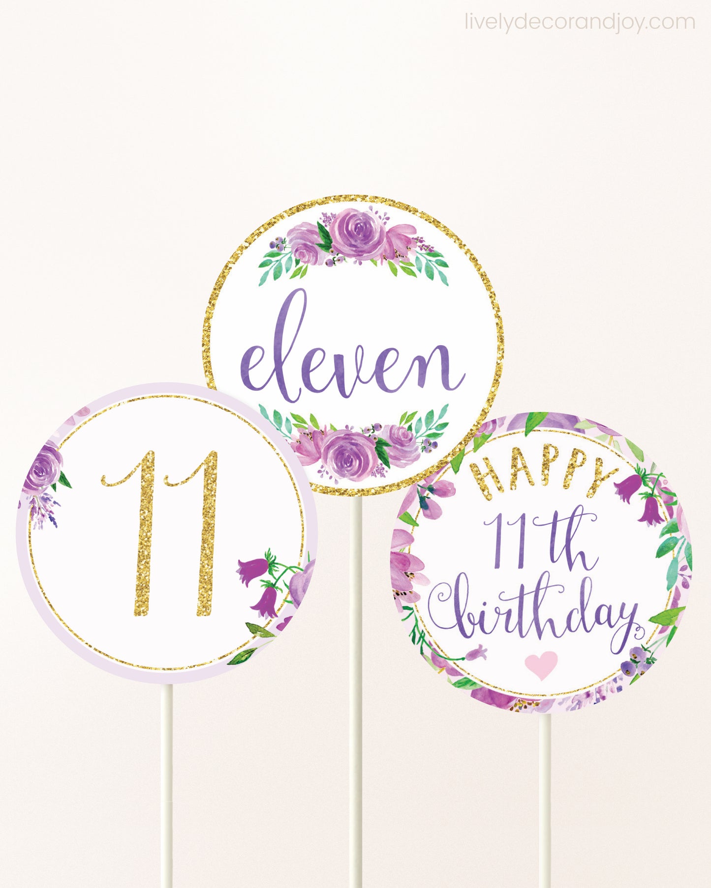 Three DIY toppers attached to lollipop sticks. They show printable cupcake topper designs with purple watercolor flowers.