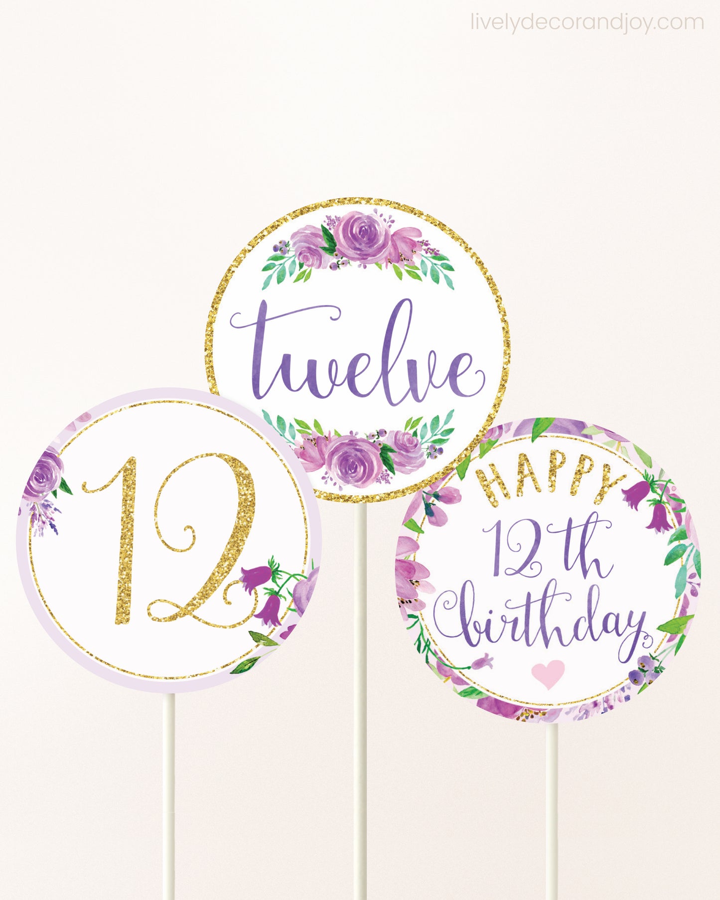 Three cupcakes toppers attached to lollipop sticks. They feature purple watercolor floral designs and purple and gold handwritten text.