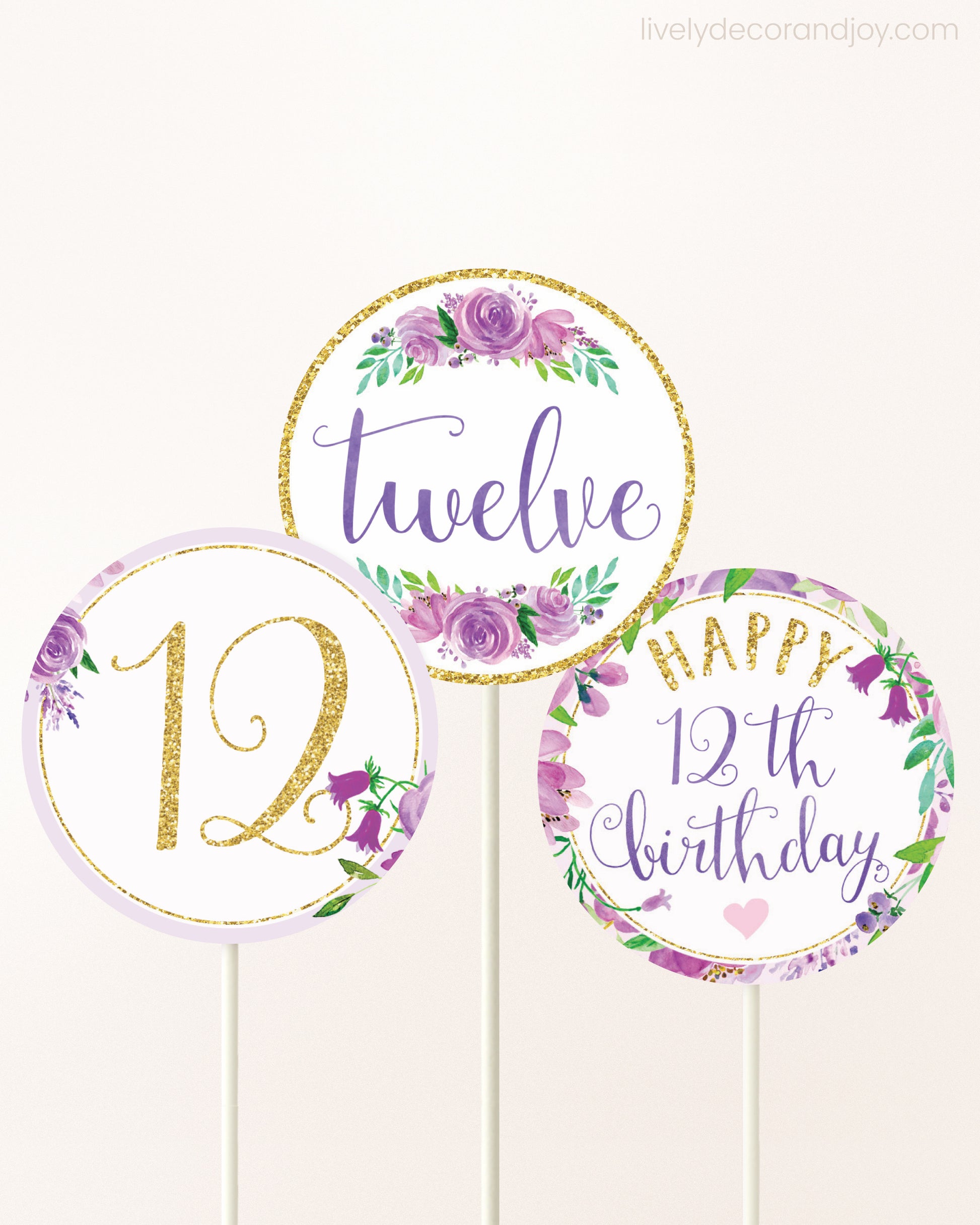 Three cupcakes toppers attached to lollipop sticks. They feature purple watercolor floral designs and purple and gold handwritten text.