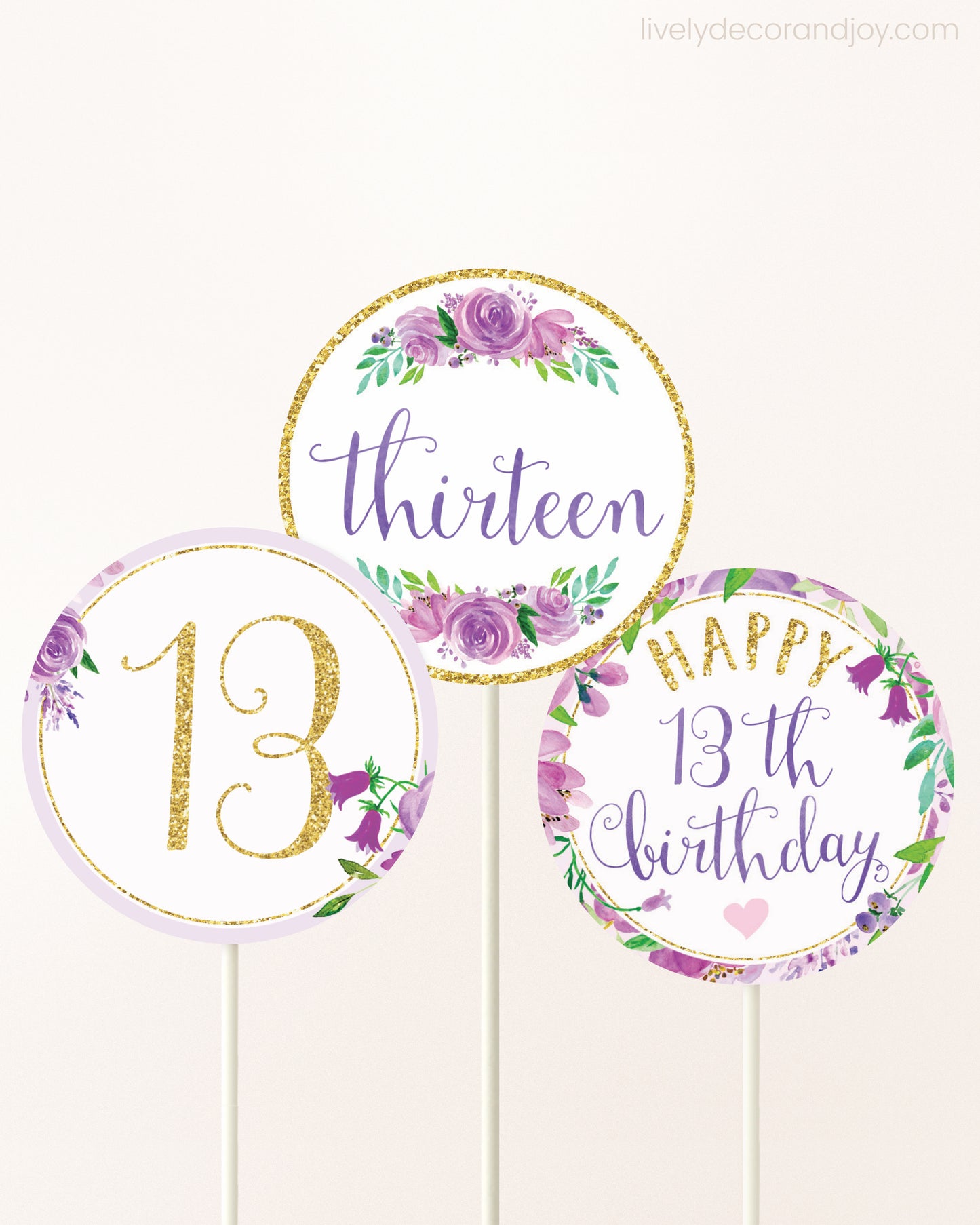 Three DIY toppers attached to lollipop sticks. They show printable cupcake topper designs with purple watercolor flowers.