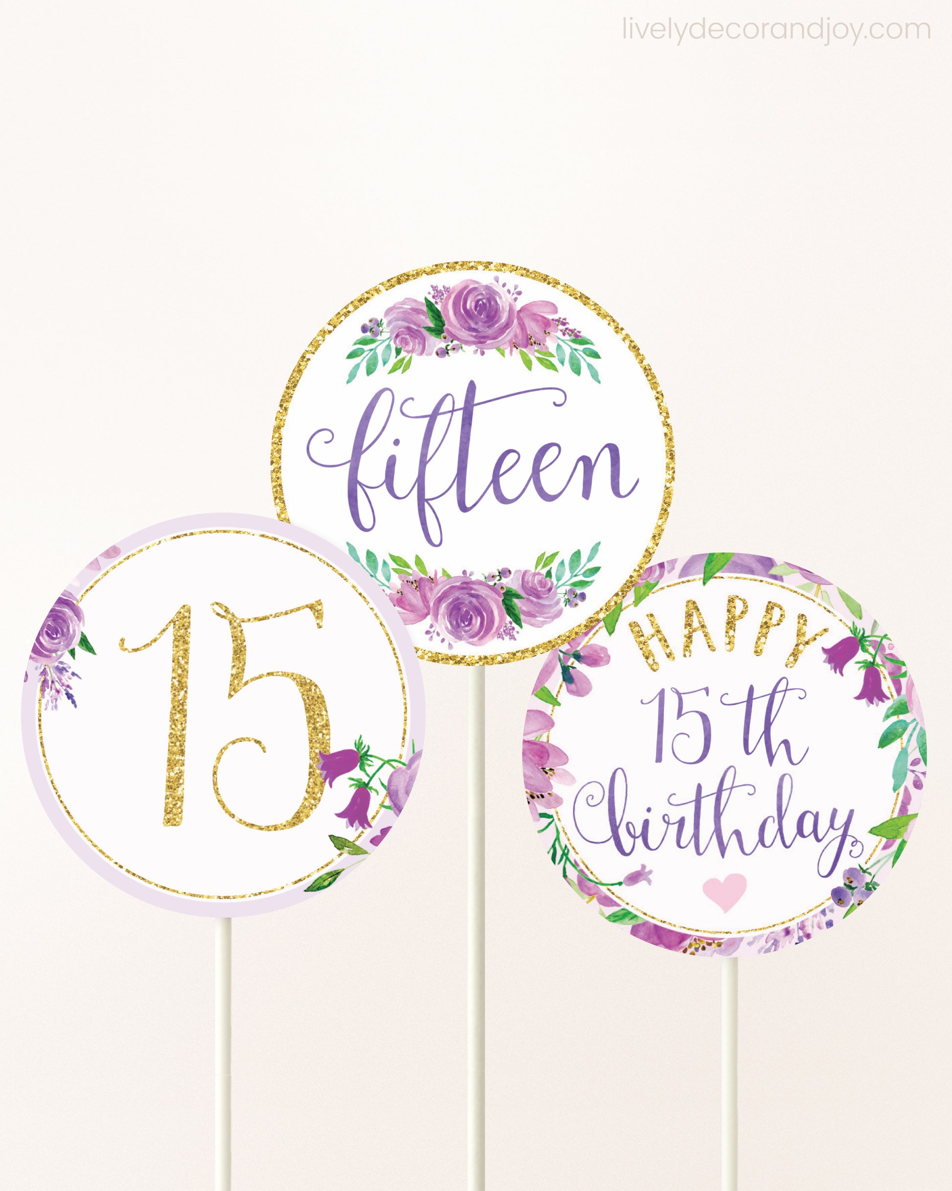 Three cupcakes toppers attached to lollipop sticks. They feature purple watercolor floral designs and purple and gold handwritten text.