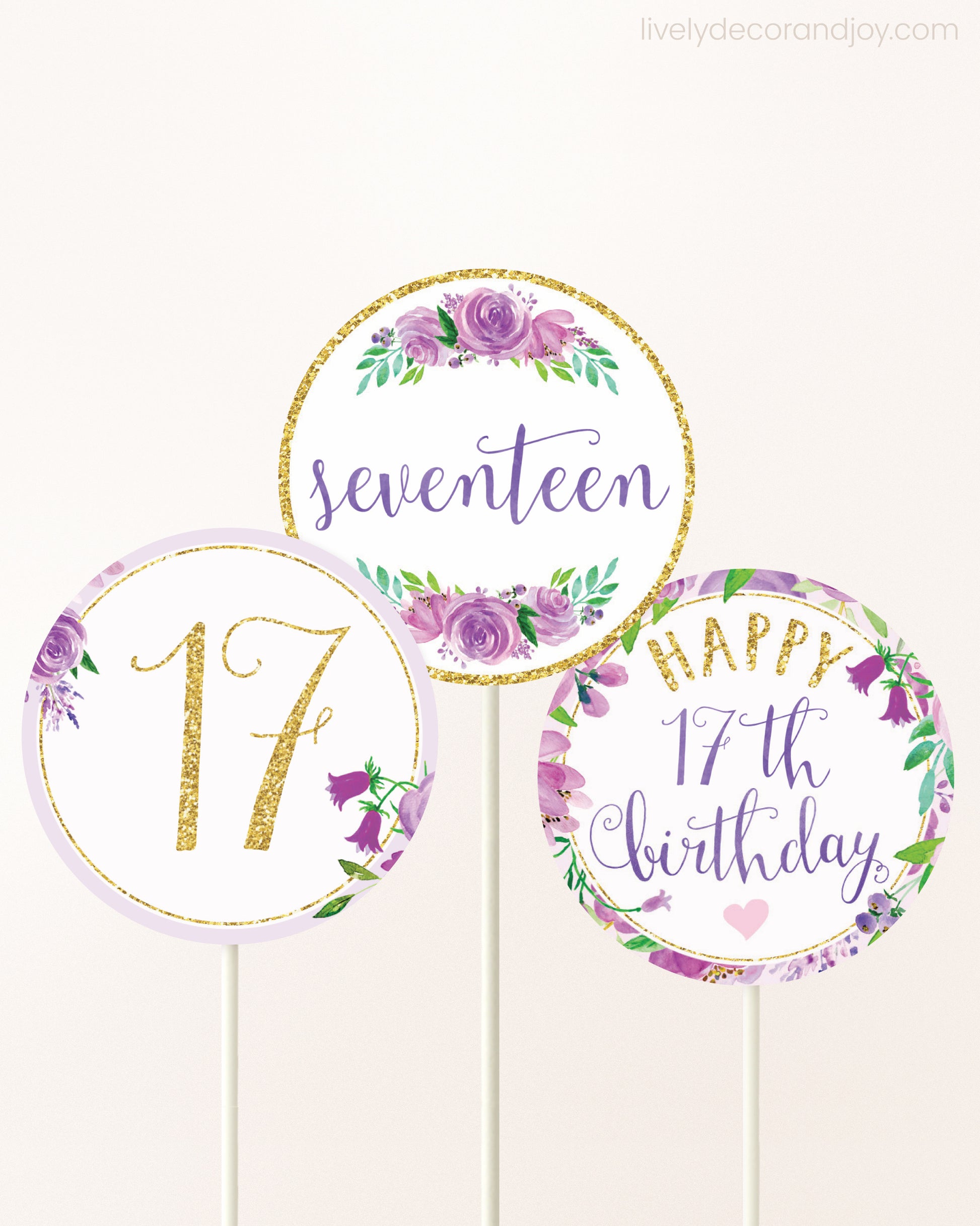 Three cupcakes toppers attached to lollipop sticks. They feature purple watercolor floral designs and purple and gold handwritten text.