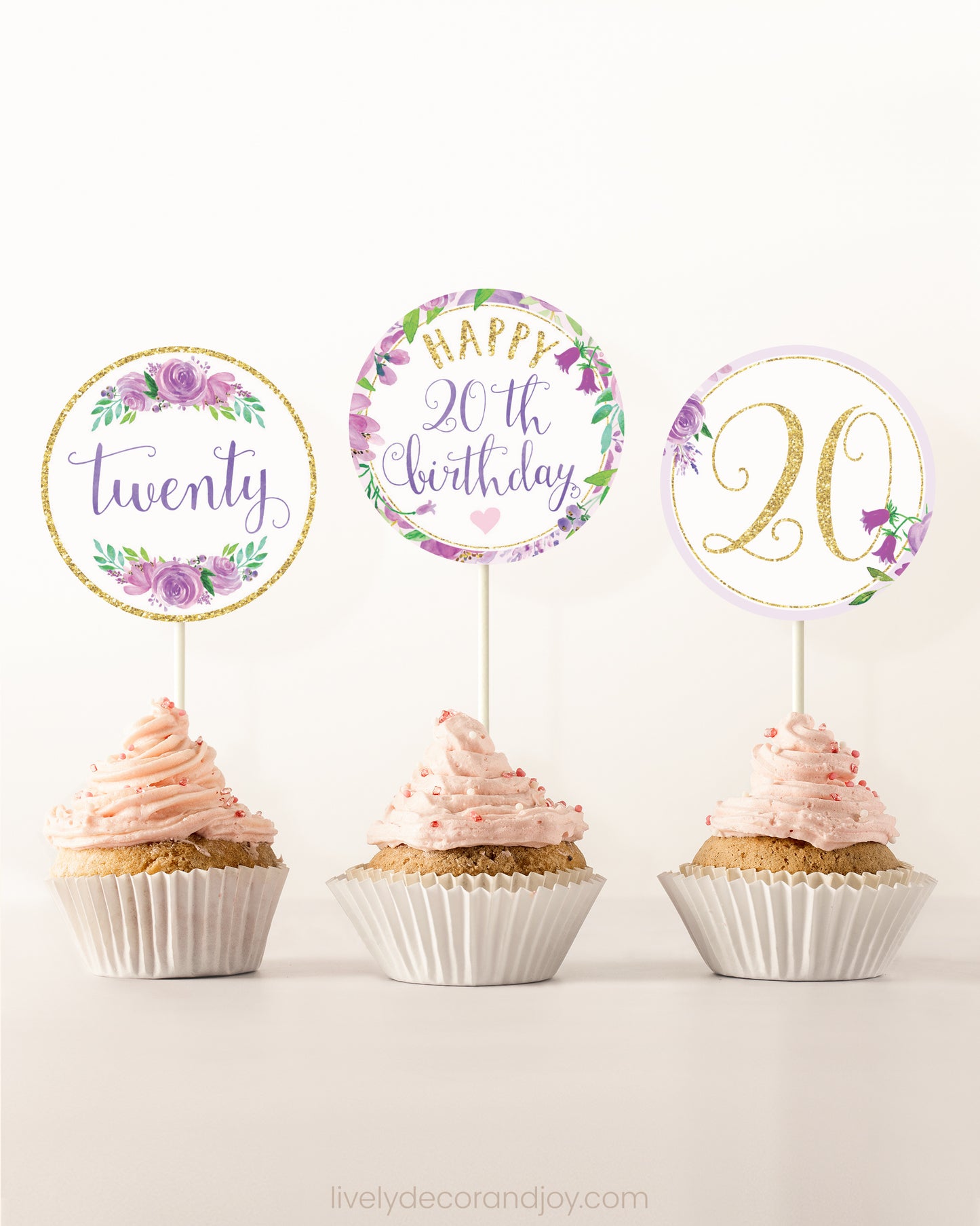 Three cupcakes on a dessert table. Each has a round cupcake topper with purple watercolor floral designs and purple and gold letters.
