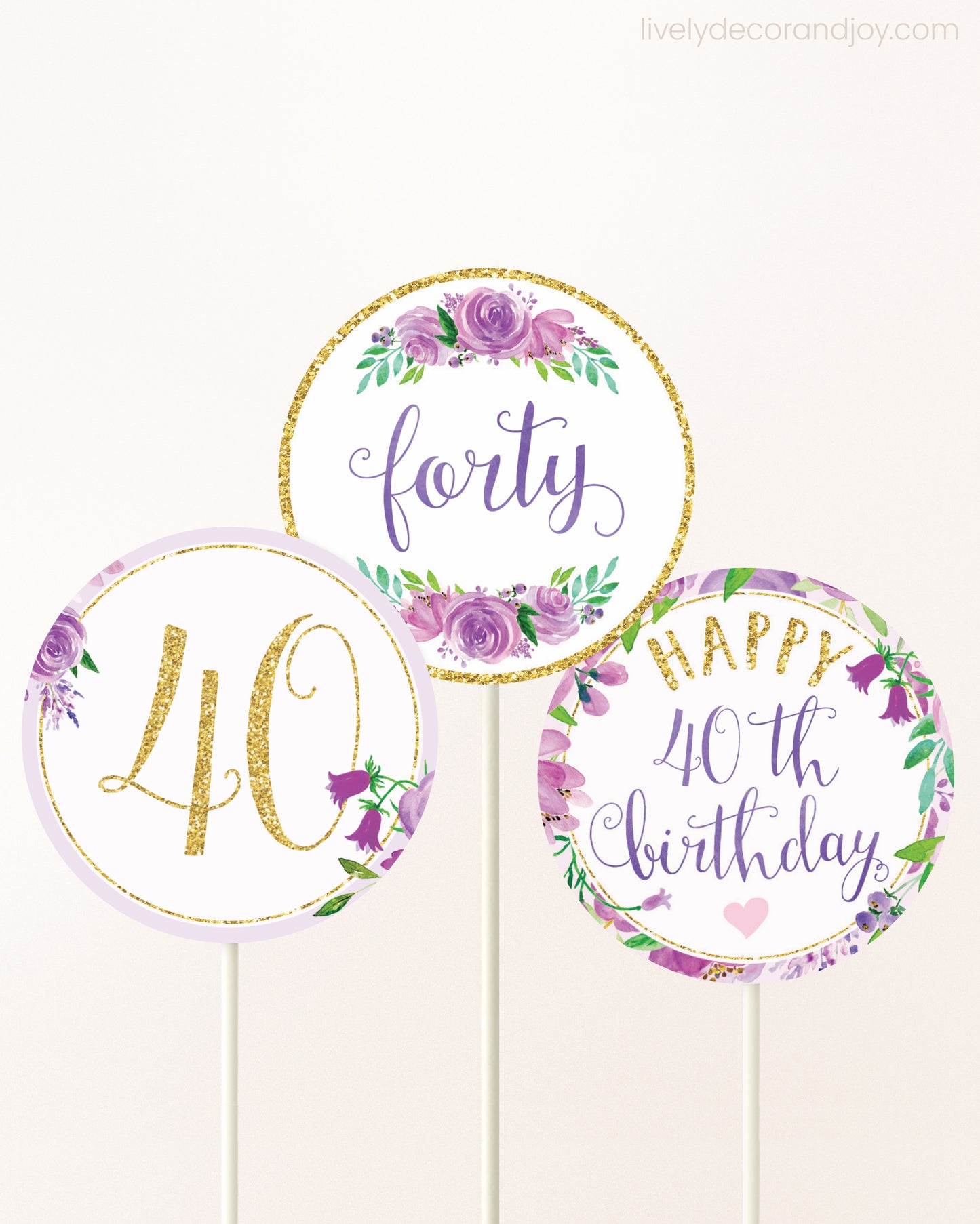 Three DIY toppers attached to lollipop sticks. They show printable cupcake topper designs with purple watercolor flowers.
