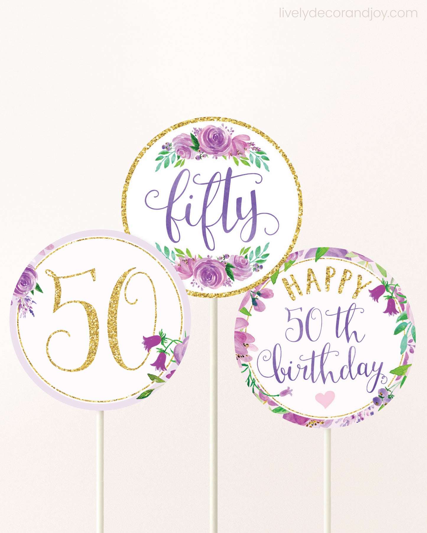 Three DIY toppers attached to lollipop sticks. They show printable cupcake topper designs with purple watercolor flowers.